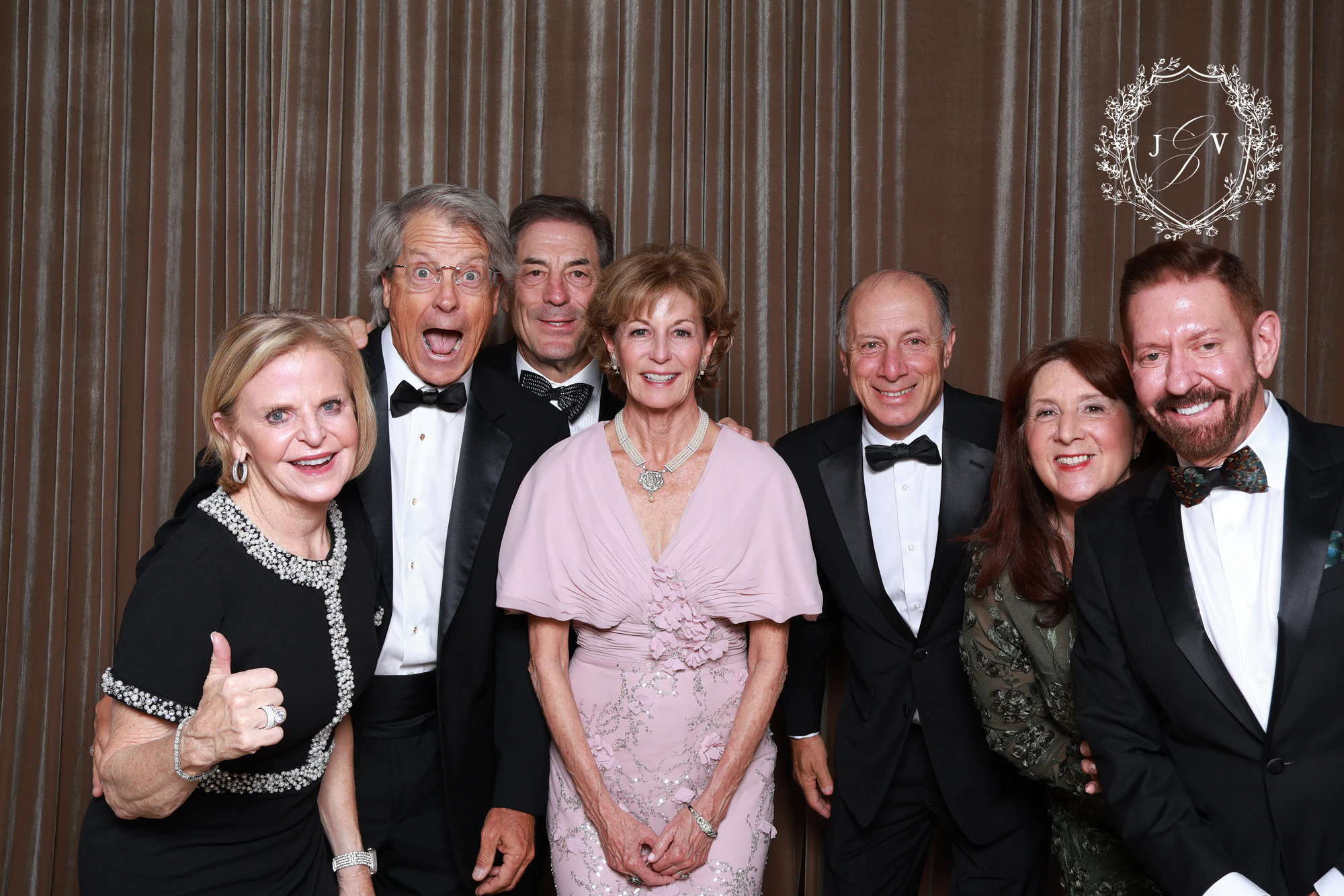 Seven guests in black tie and pink in a row, smiling at Nash Gaurino Wedding