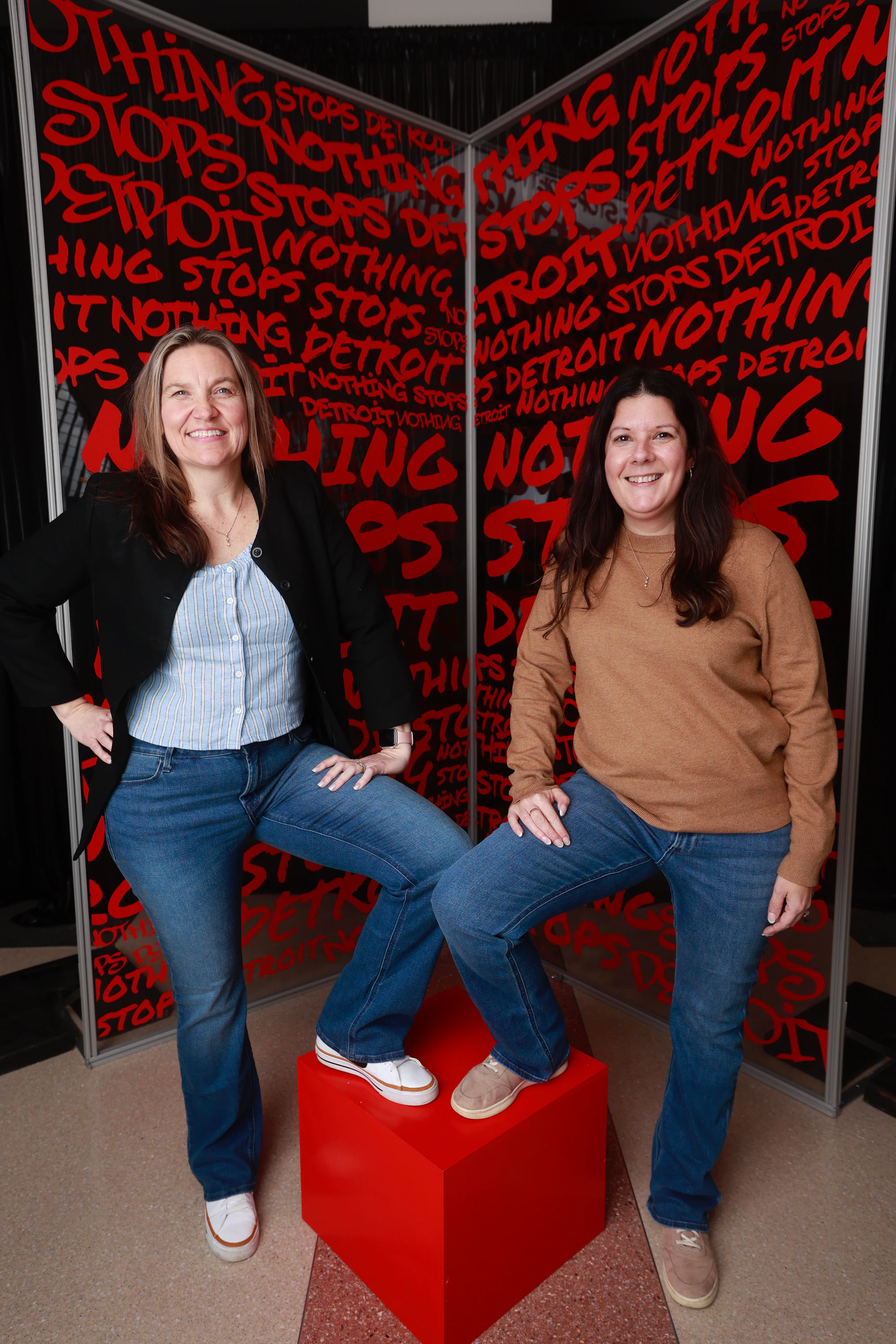 Two women with a foot up on the red cube at Nothing Stops Detroit