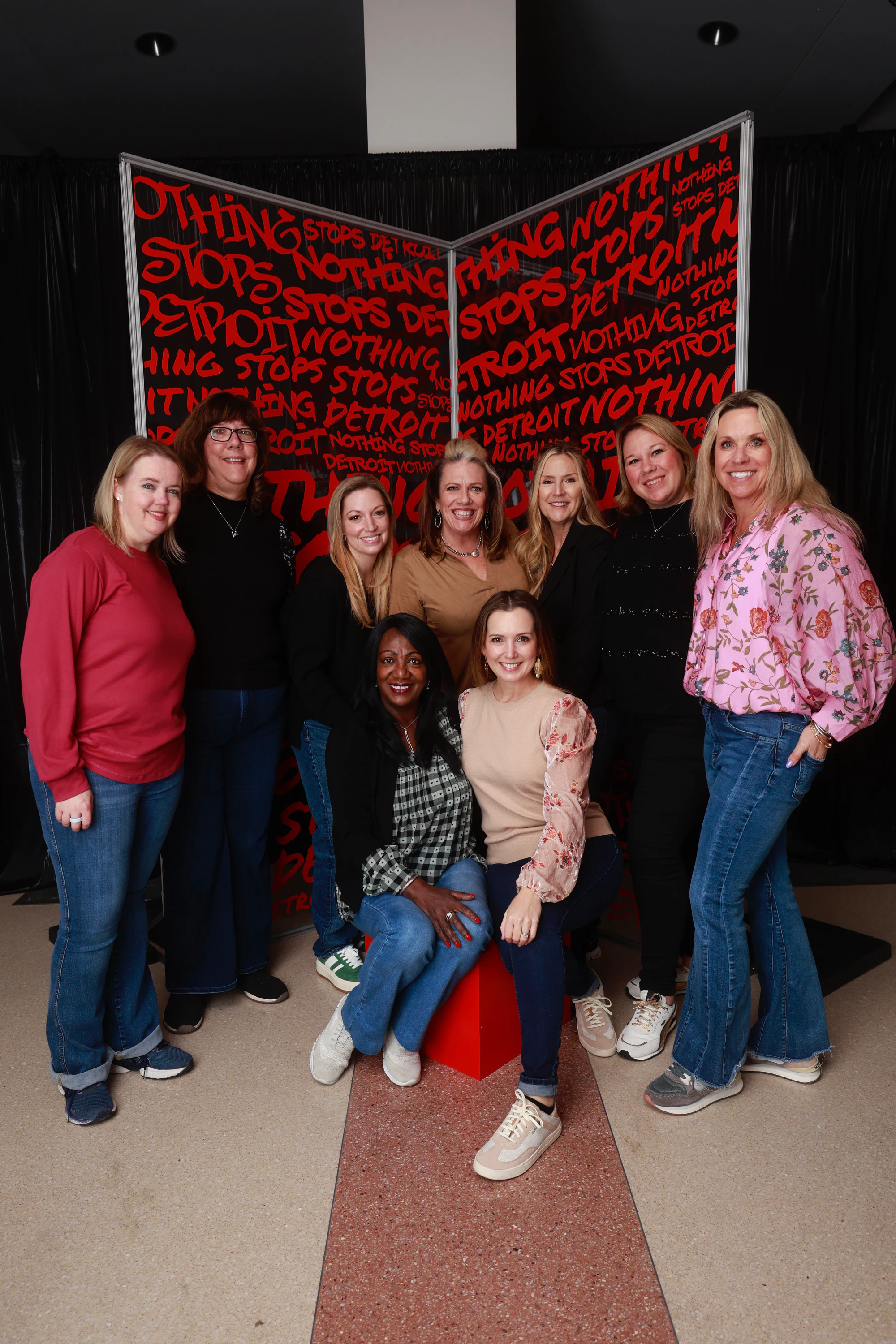Eight women layered front to back, all smiling at Nothing Stops Detroit