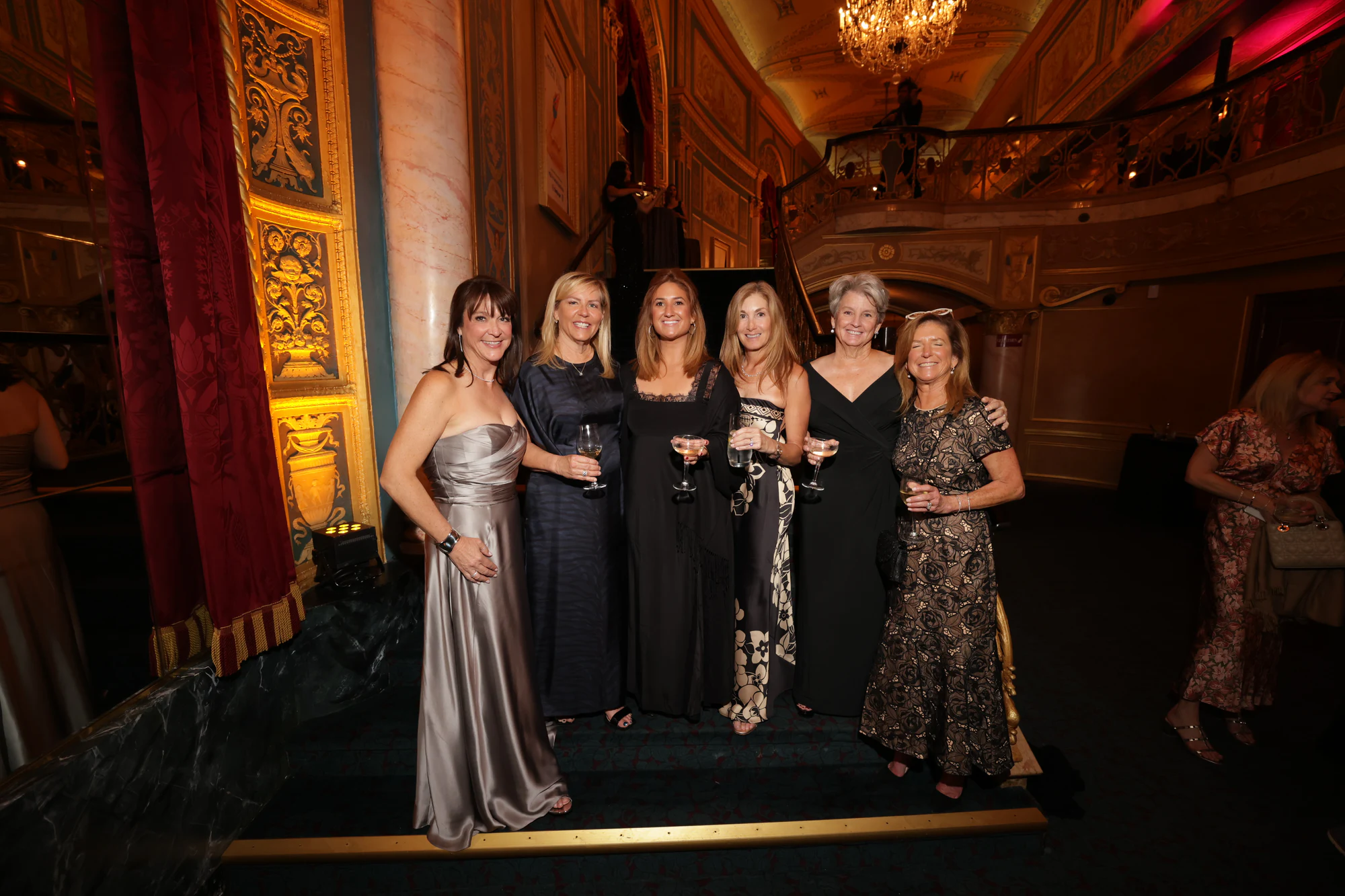 Six guests in gowns with champagne on the stairs at Engagement Party Surprise at the Detroit Opera House