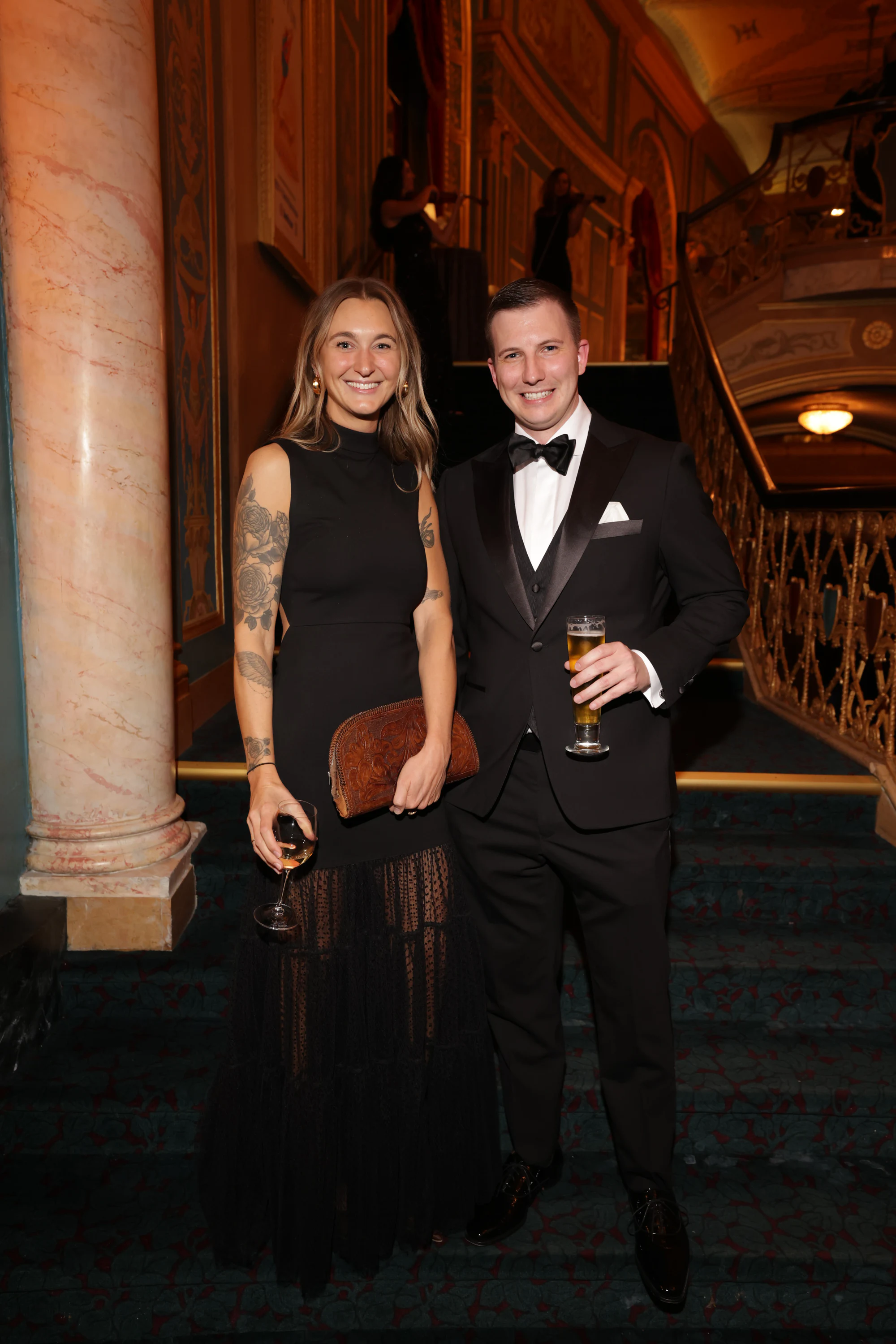 A couple by the marble column, her in a black lace gown at the surprise engagement party at the Detroit Opera House