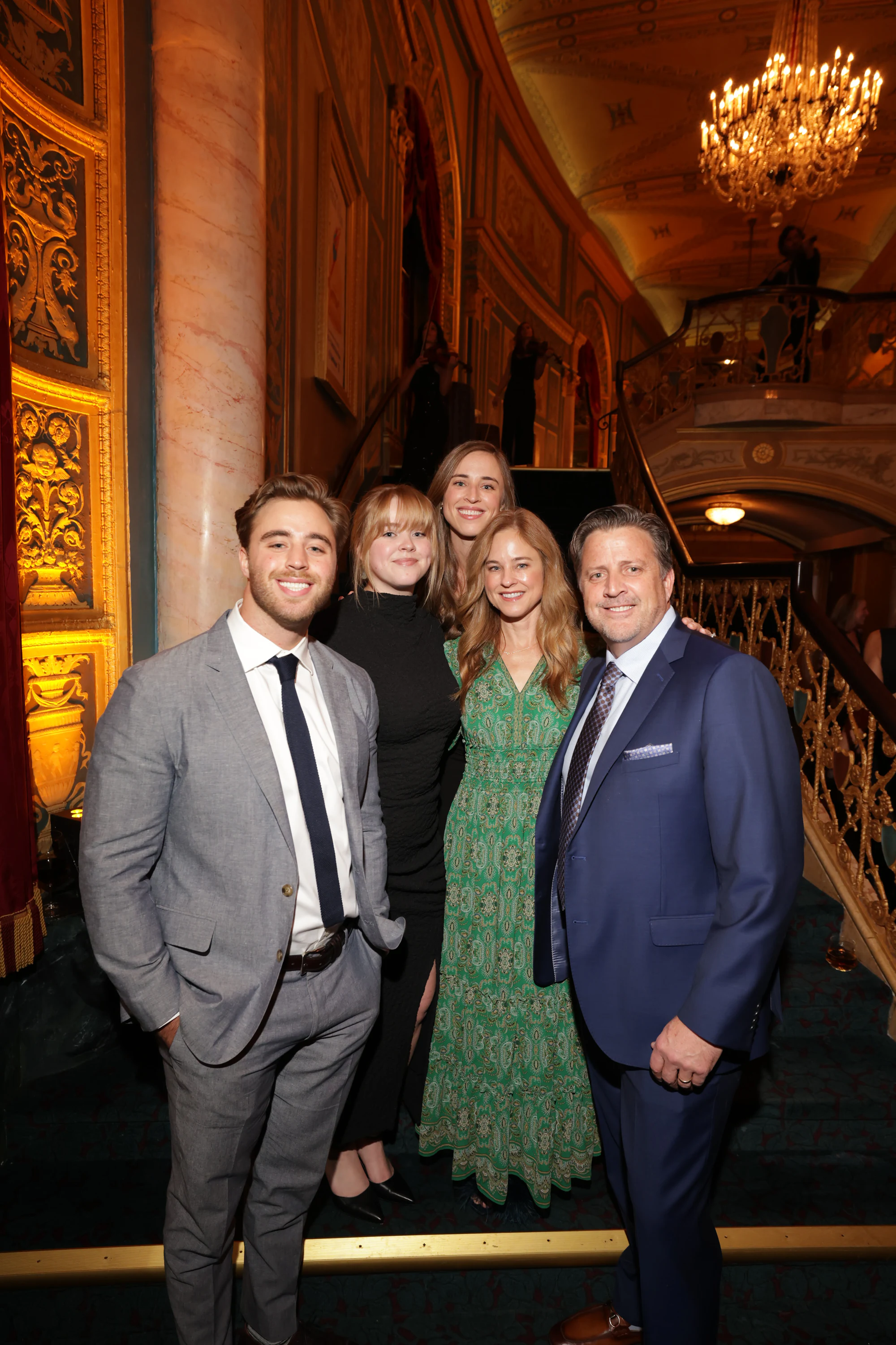 Five guests on the grand staircase, two in suits at Surprise Engagement at the Opera House