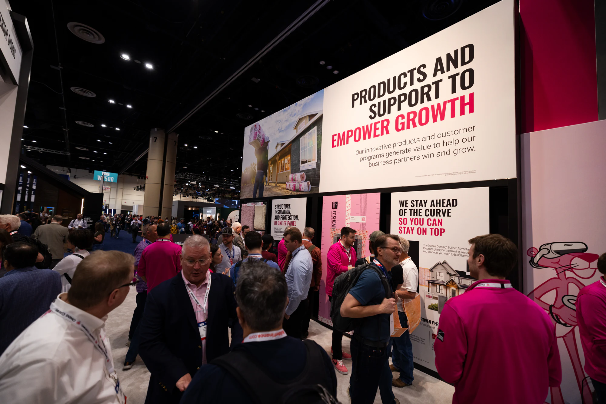 Wide of the Empower Growth wall with the aisle full at Owens Corning at IBS 2026