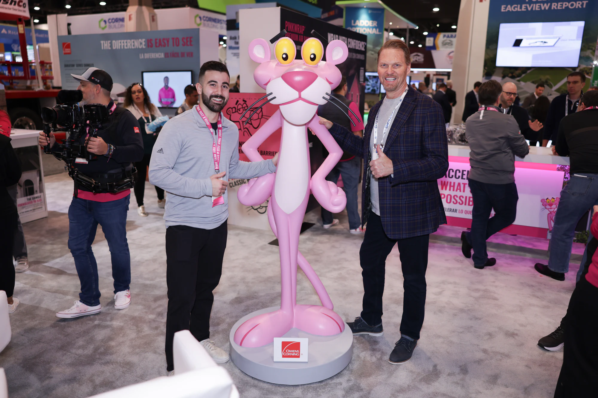 The Pink Panther statue in the booth with two visitors at Owens Corning at IRE 2024