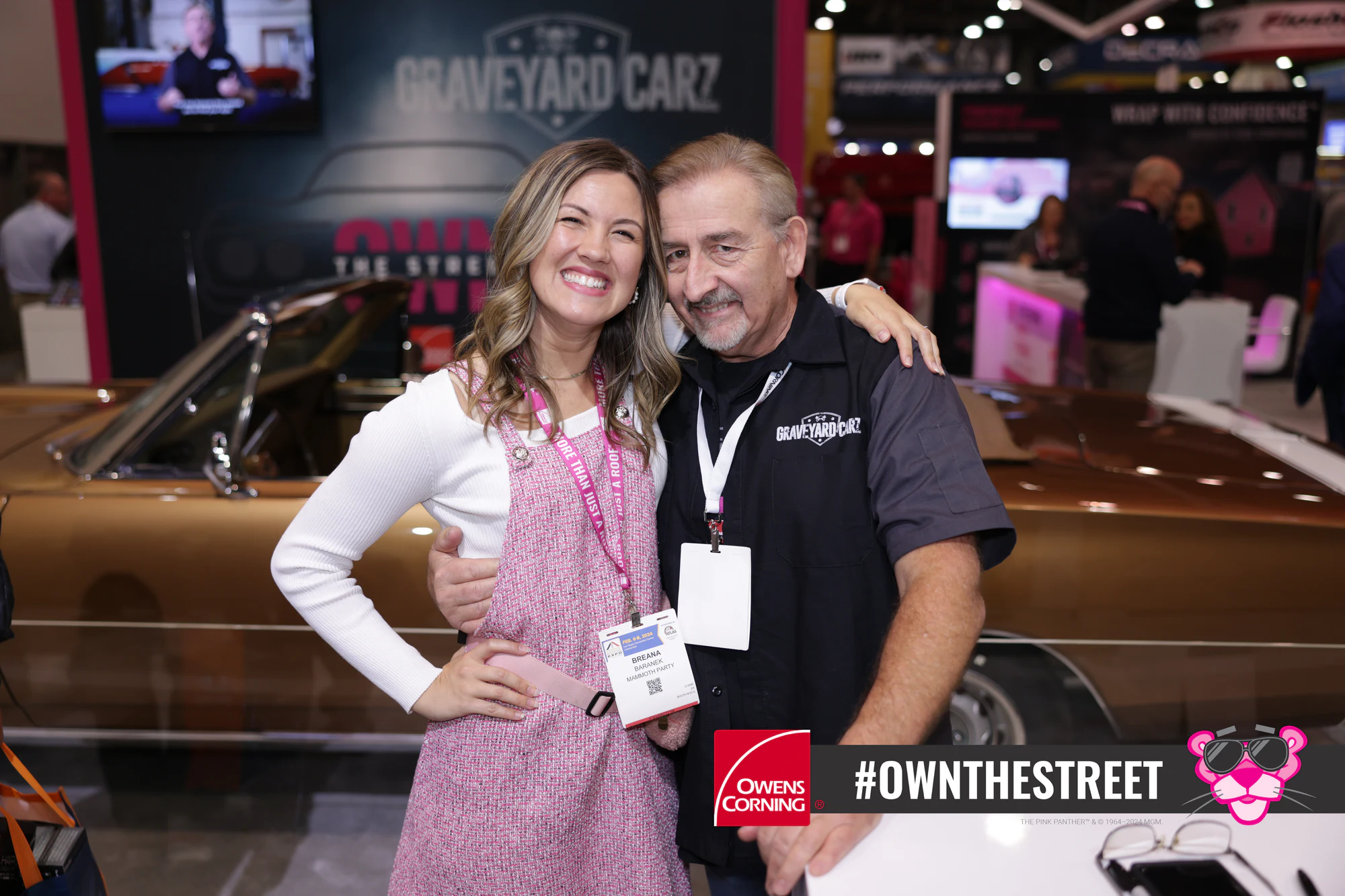 A Mammoth crew member in Owens Corning pink with a guest in a Graveyard Carz shirt on the show floor at Owens Corning at IRE 2024