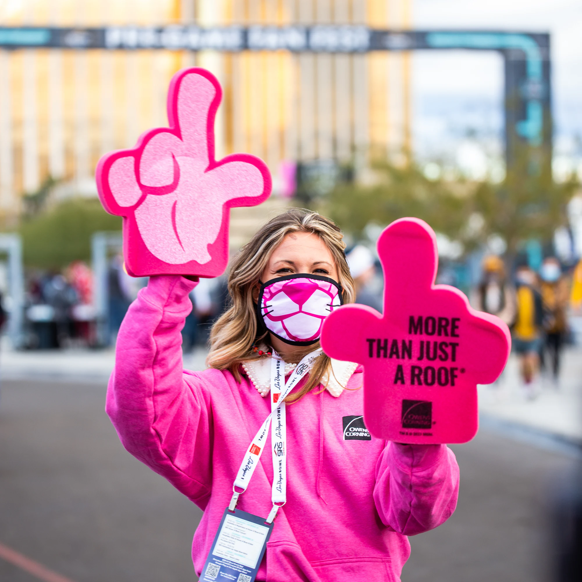 Woman in a Pink Panther mask waving two pink foam hands on the walk into Fan Fest at Owens Corning at the 2021 Las Vegas Bowl