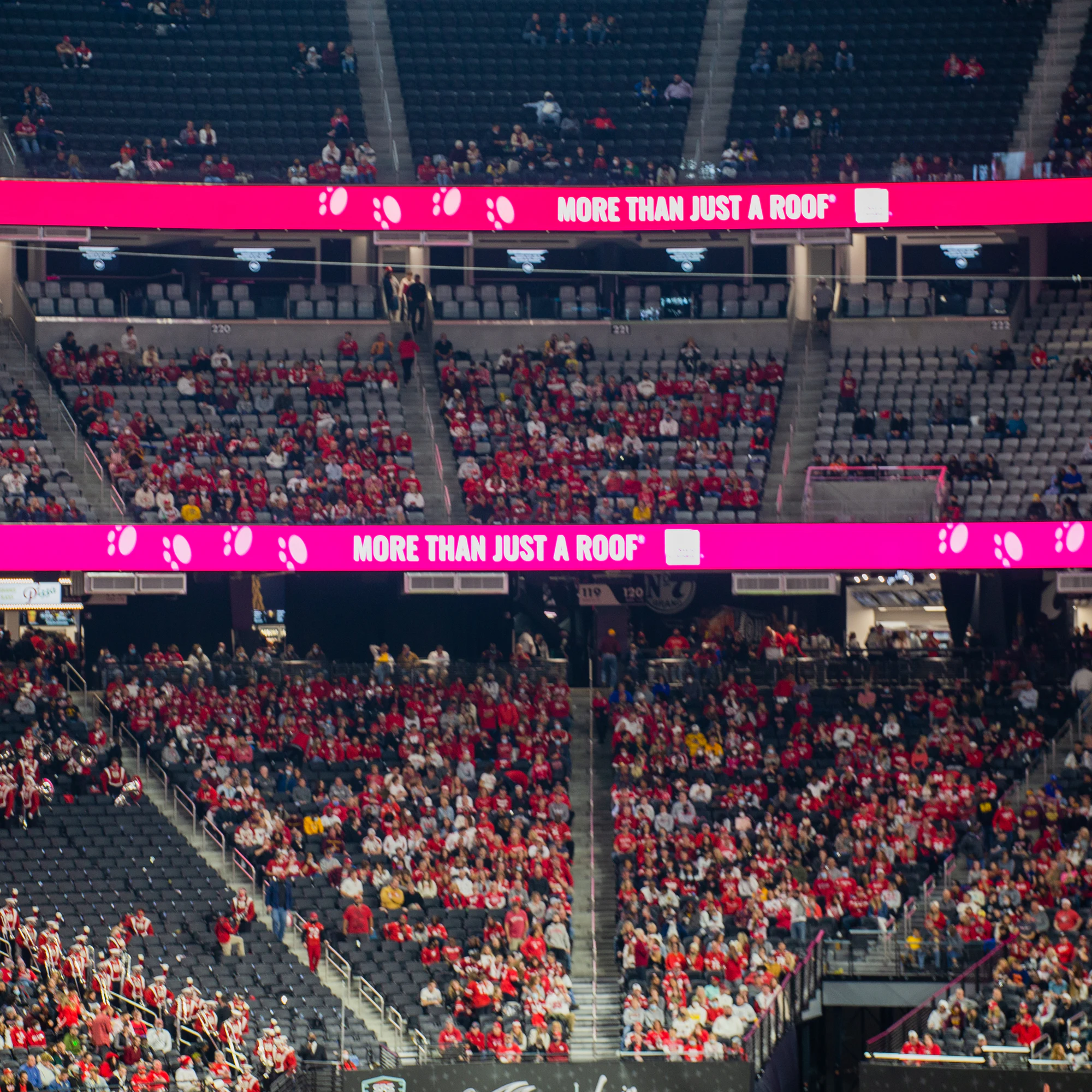 More Than Just a Roof ribbon boards wrapped around stands full of fans in red at Owens Corning at the 2021 Las Vegas Bowl