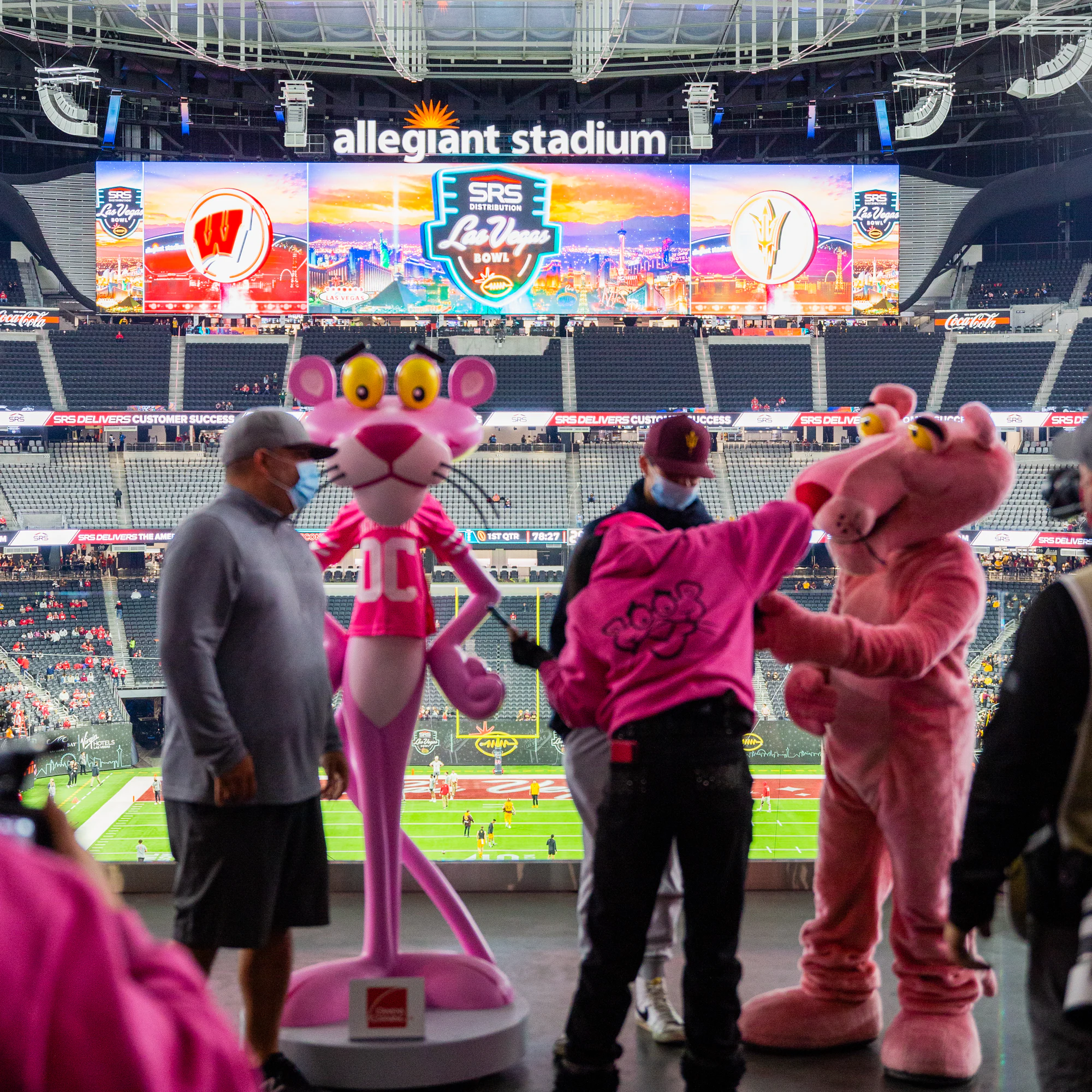 Pink Panther mascot and statue posing with guests, Las Vegas Bowl scoreboard behind at Owens Corning at the 2021 Las Vegas Bowl
