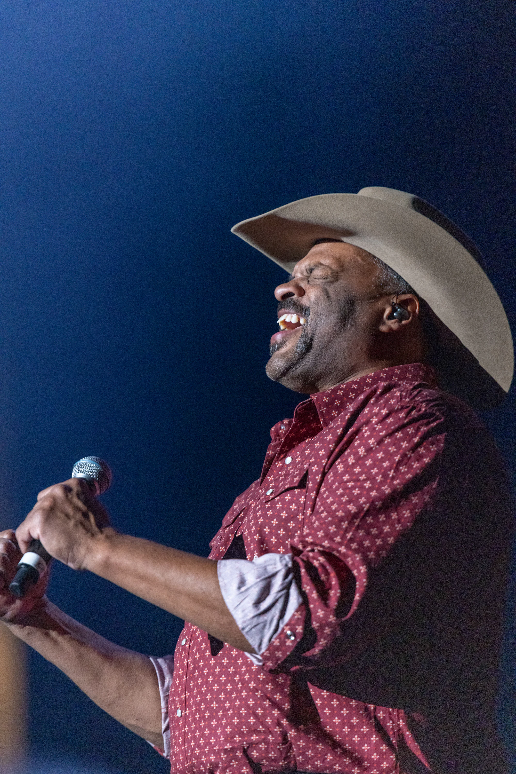 Singer in a white cowboy hat laughing into the microphone at Owens Corning at the 2022 Las Vegas Bowl