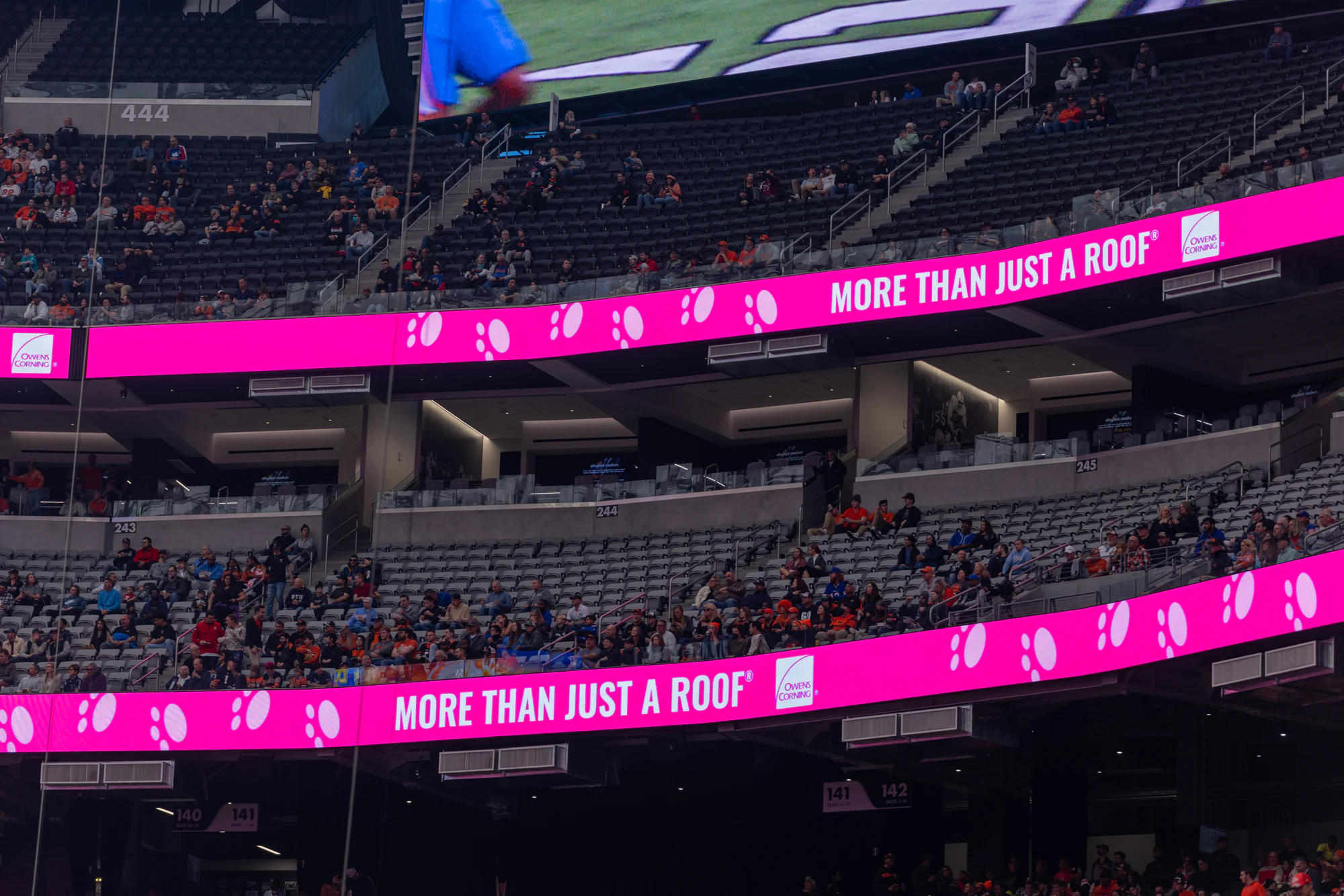 Two pink More Than Just A Roof ribbon boards wrapping the stadium seats at Owens Corning at the 2022 Las Vegas Bowl