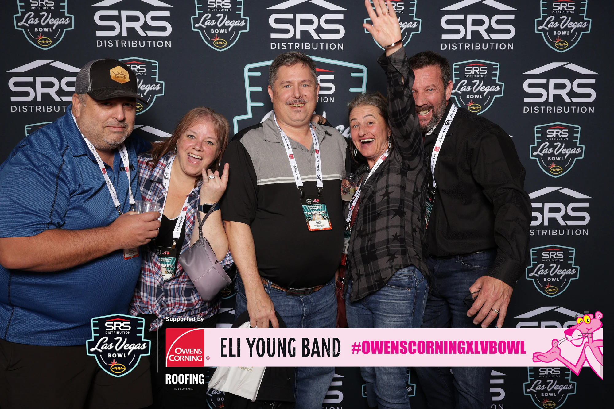Six at the SRS Distribution wall, one of them waving at Owens Corning at the 2023 Las Vegas Bowl