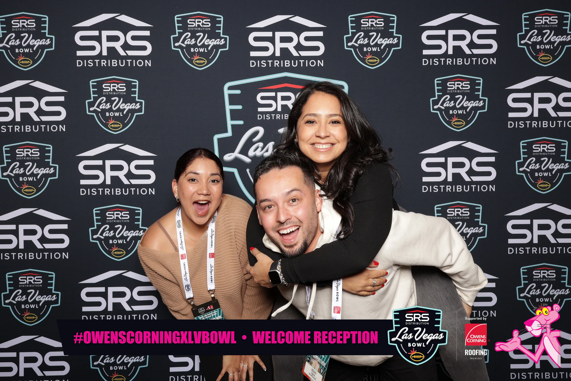 Woman riding piggyback on a grinning man while her friend cracks up beside them, SRS and Las Vegas Bowl backdrop at Owens Corning at the 2023 Las Vegas Bowl