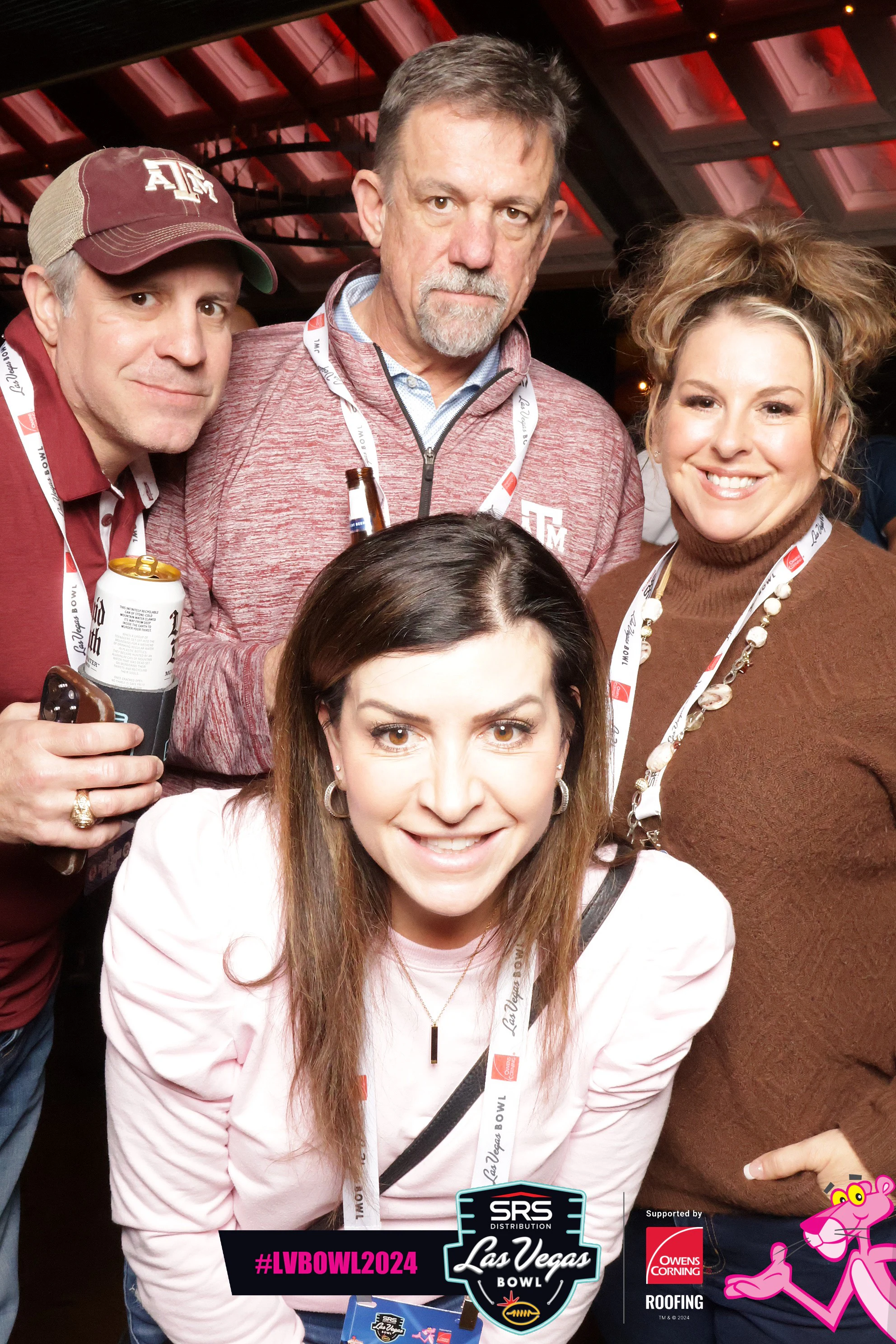 Four guests in Texas A&M maroon lean in close, all smiling at the camera at Owens Corning at the 2024 Las Vegas Bowl