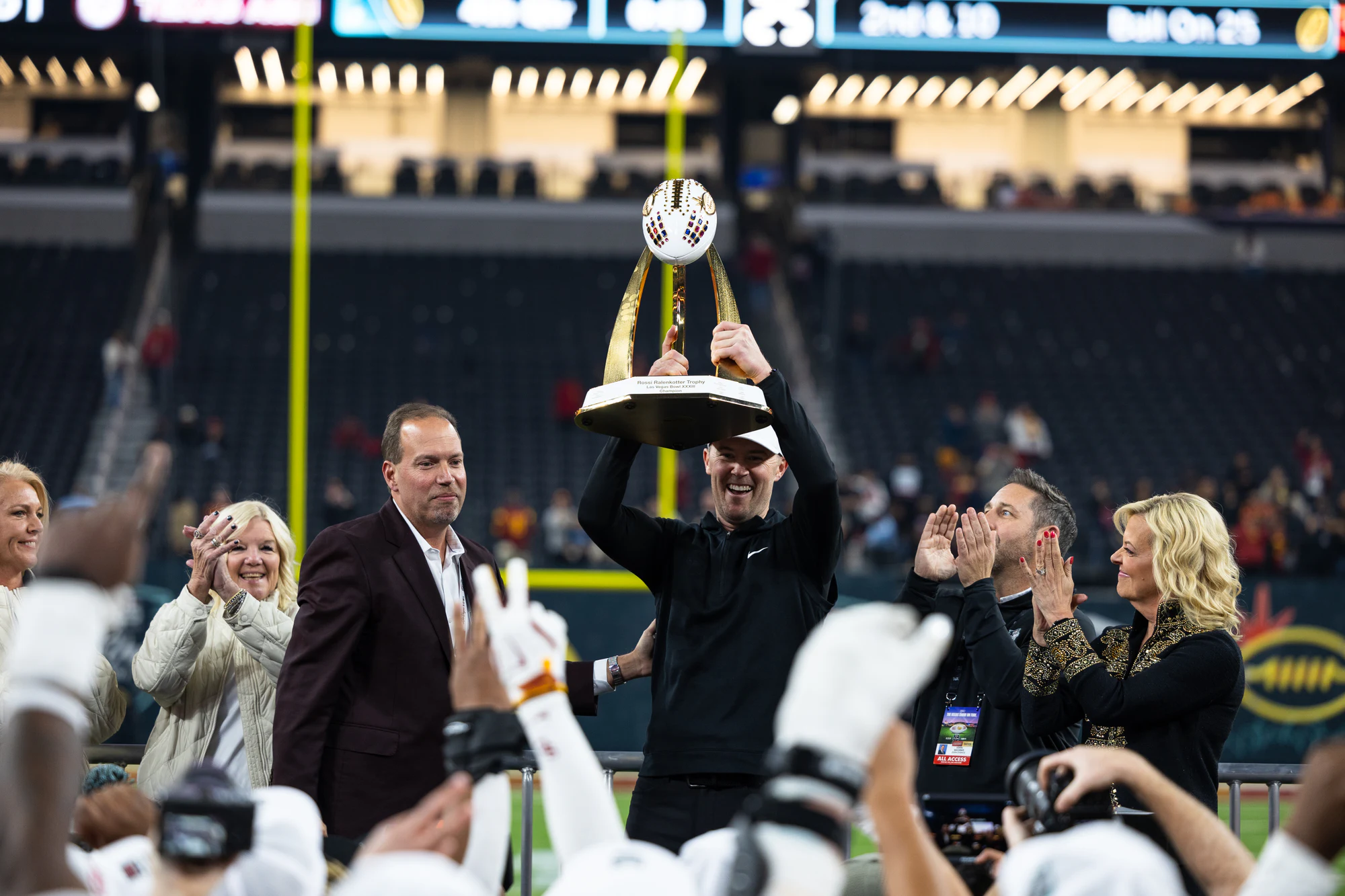 The trophy goes up overhead on the postgame stage as the crowd cheers at Owens Corning at the 2024 Las Vegas Bowl