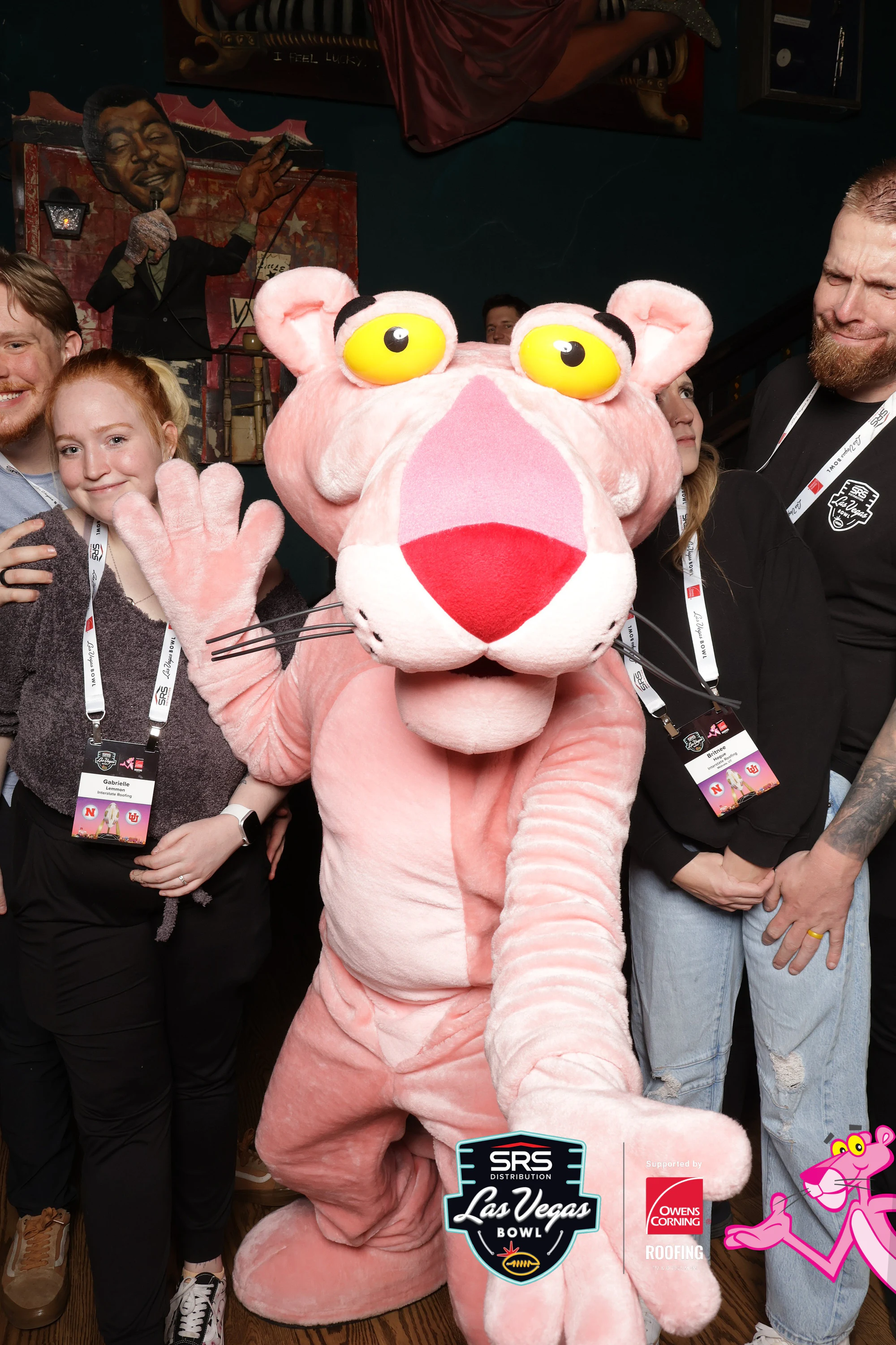 The Pink Panther reaching toward the lens with guests squeezed in around it at Owens Corning at the 2025 Las Vegas Bowl