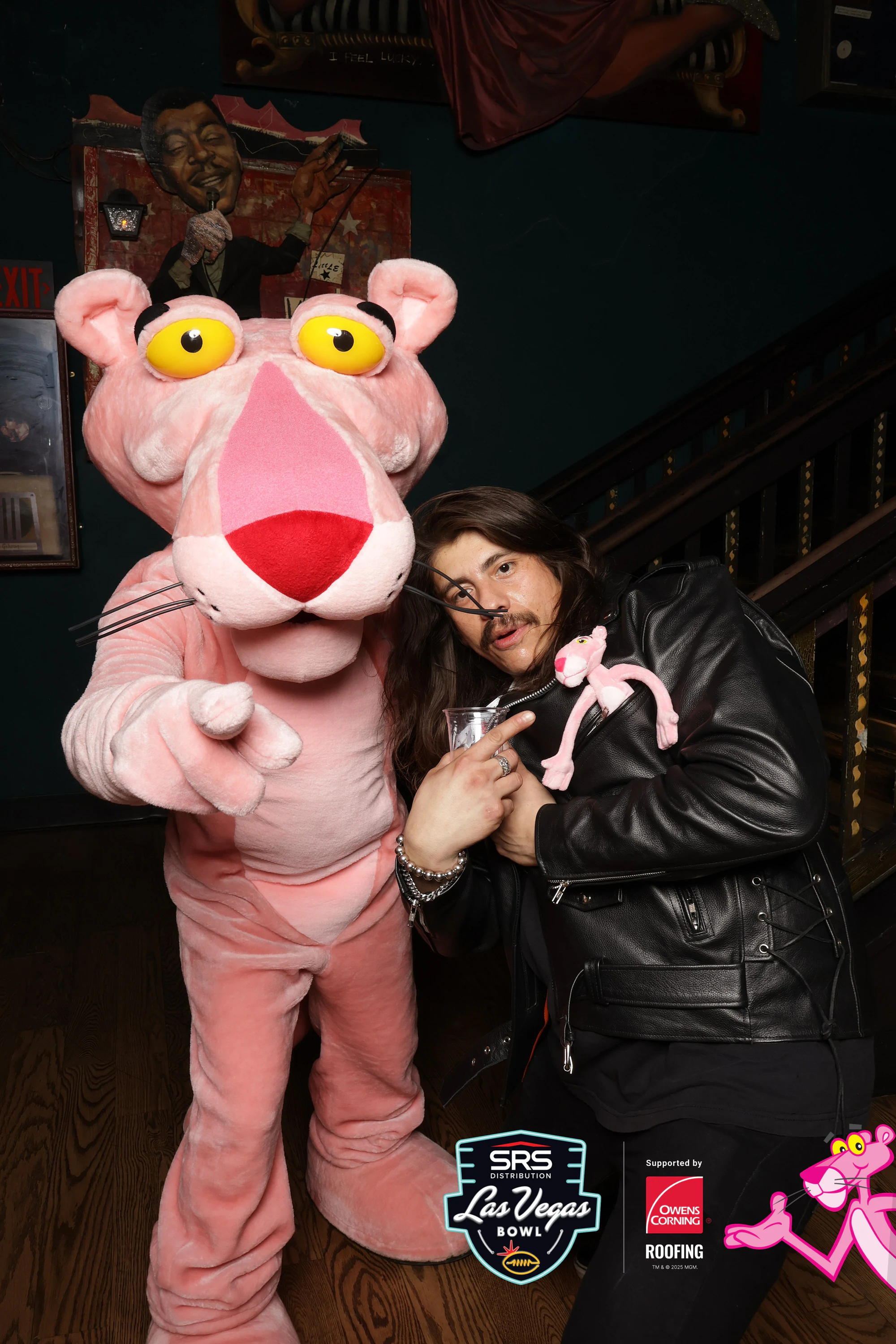 Pink Panther pointing at the lens while a guest leans in at Owens Corning at the 2025 Las Vegas Bowl