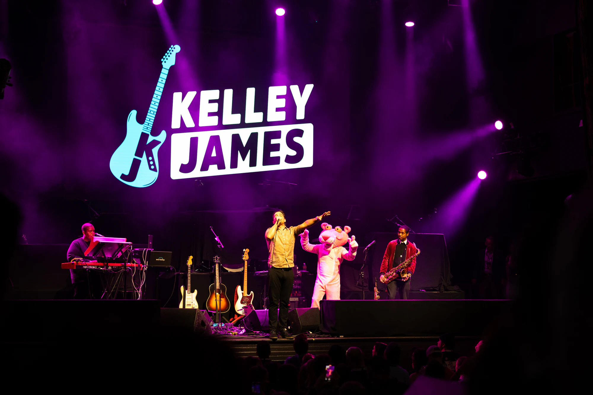 Pink Panther on stage with the band under the Kelley James sign at Owens Corning at the 2025 Las Vegas Bowl
