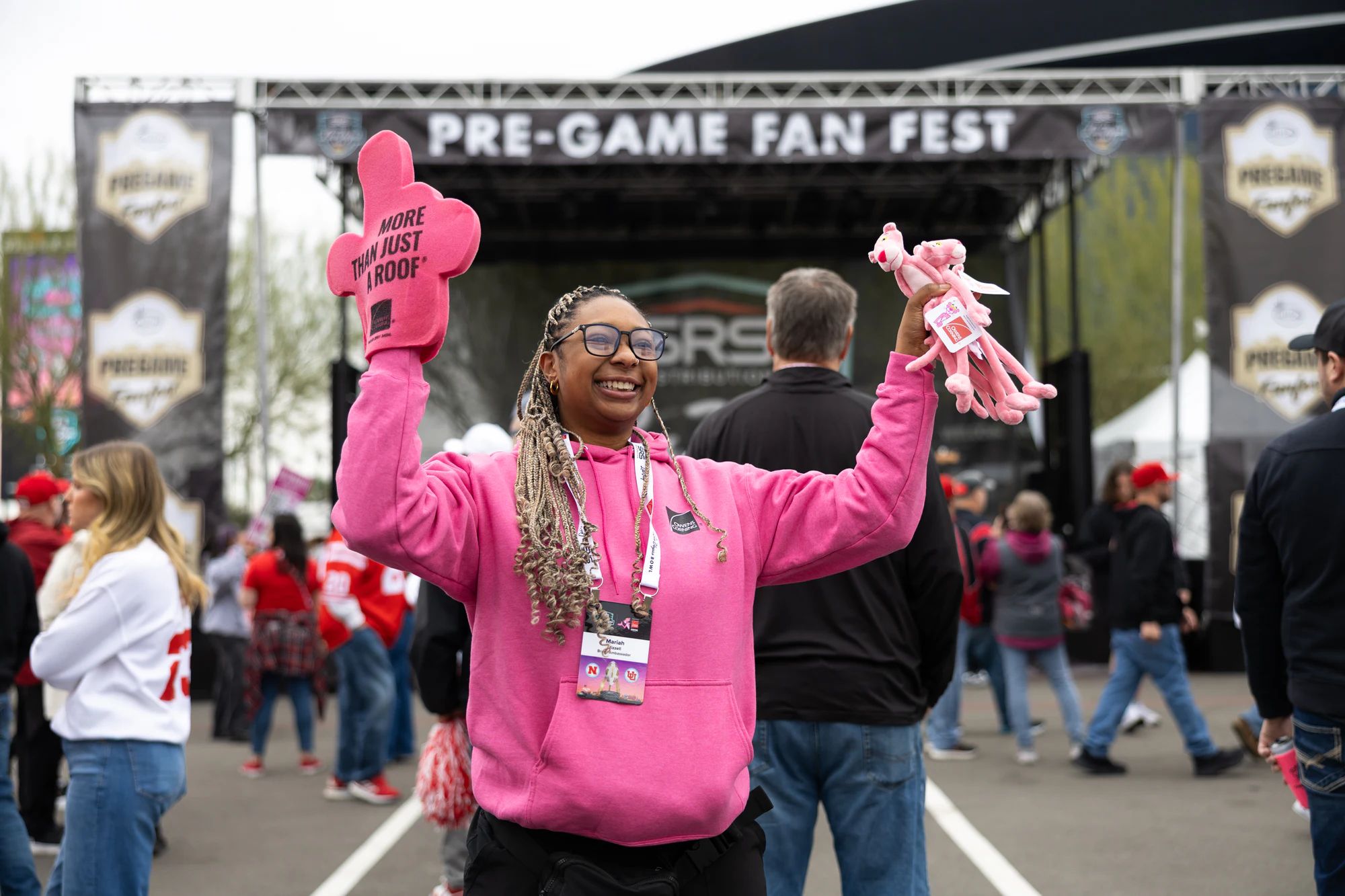 The same fan with both arms up, smiling at the camera at Owens Corning at the 2025 Las Vegas Bowl