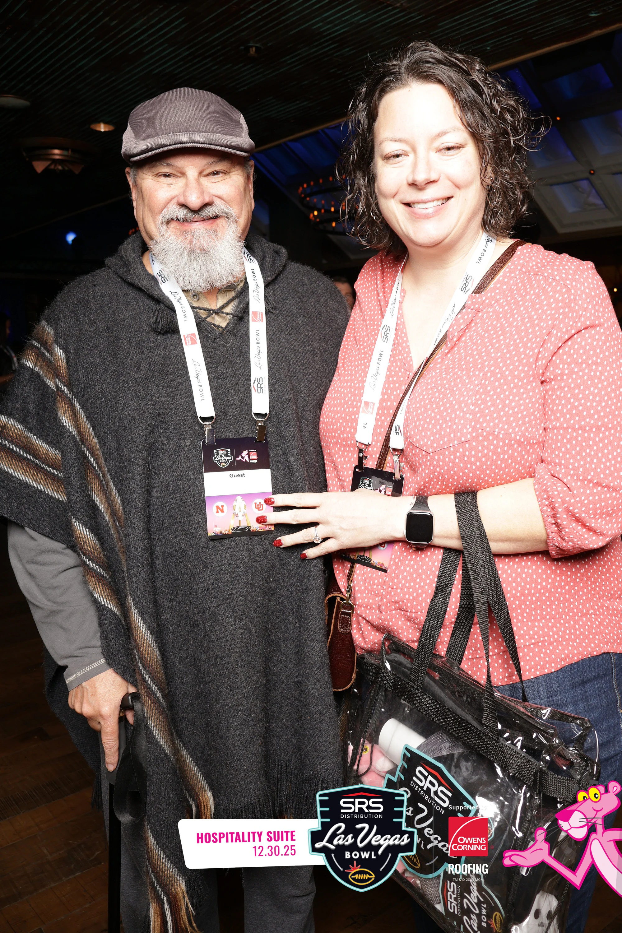 A bearded man in a gray cap and a woman in a pink top at the Hospitality Suite booth at Owens Corning at the 2025 Las Vegas Bowl
