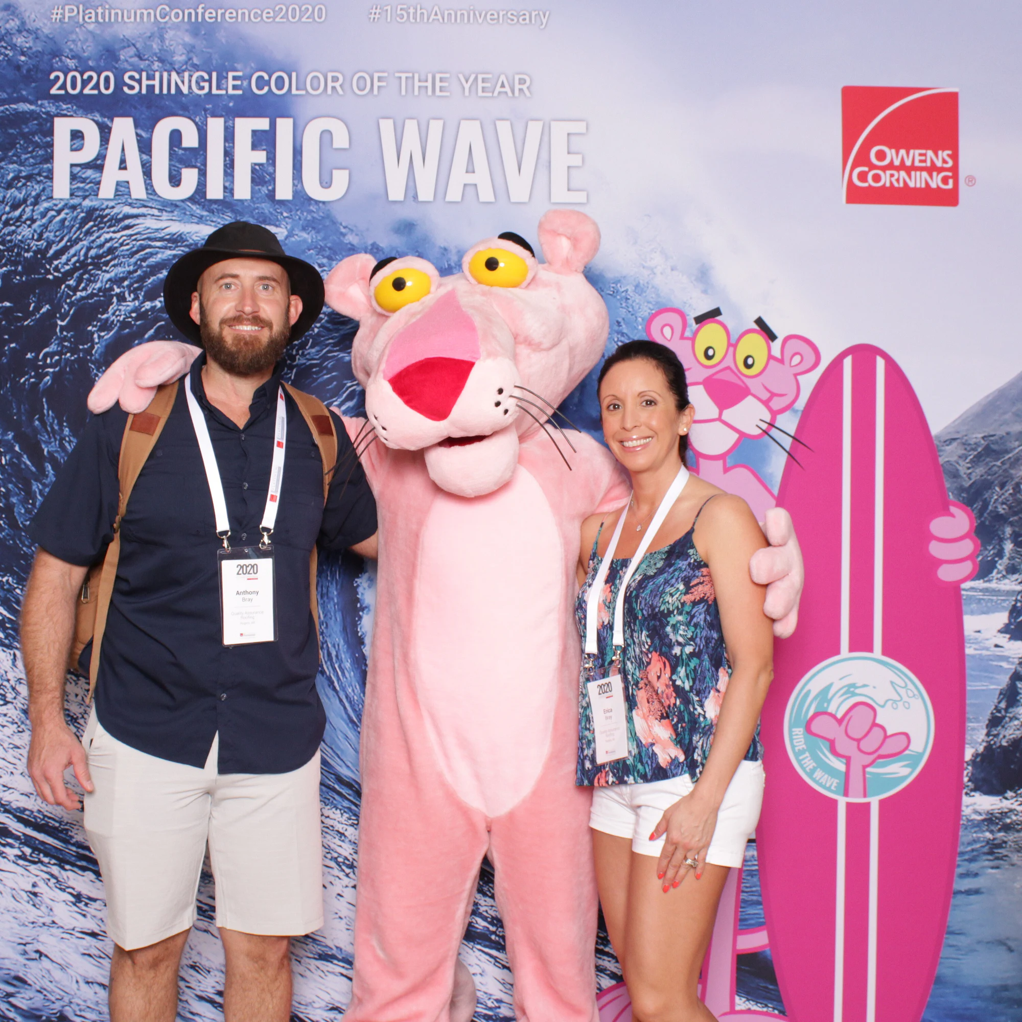 A man in a black hat and a woman in a floral top on either side of the Pink Panther at Owens Corning Platinum Conference
