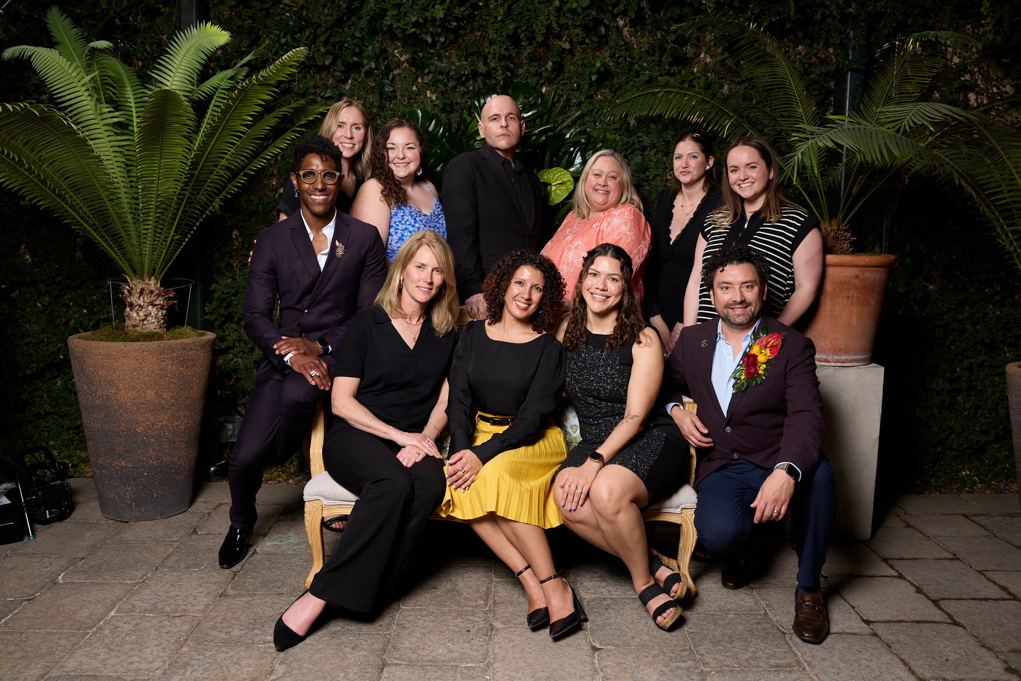 Eleven people posed on a bench among the palms at the Planterra Open House