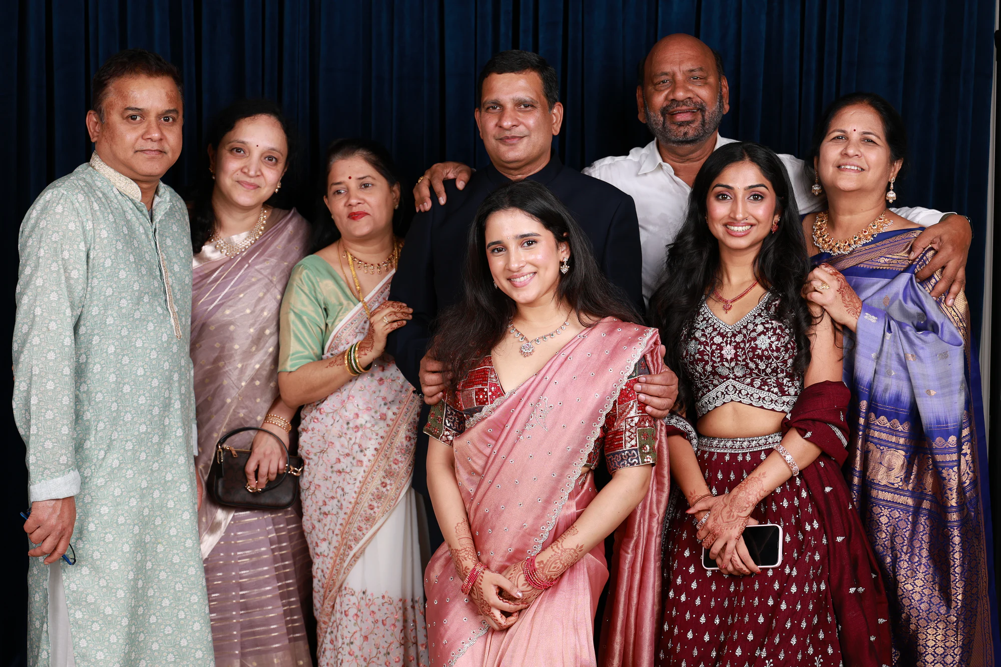 Multi-generation family group, nine people, everyone looking at Ramya + Sreehari
