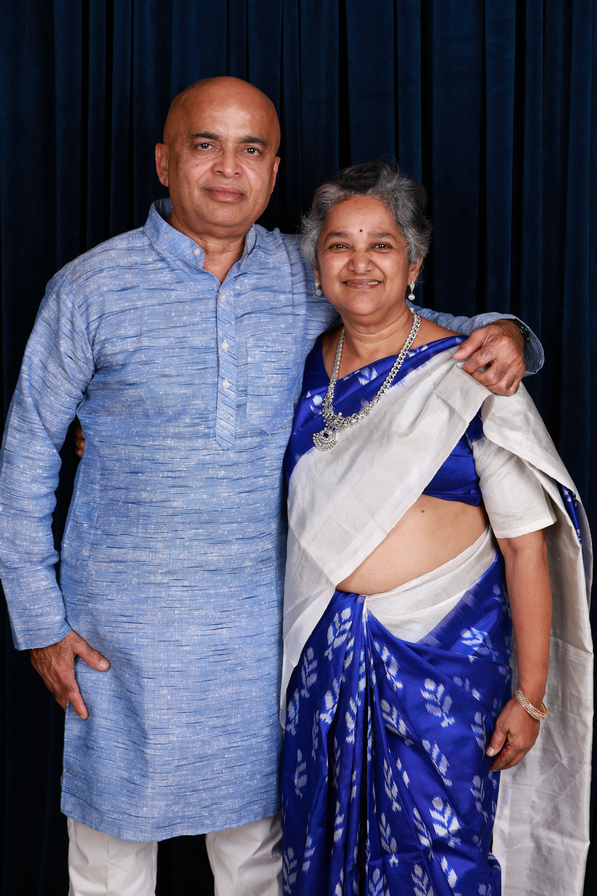 Older couple in a blue kurta and blue sari, hand on shoulder at Ramya + Sreehari