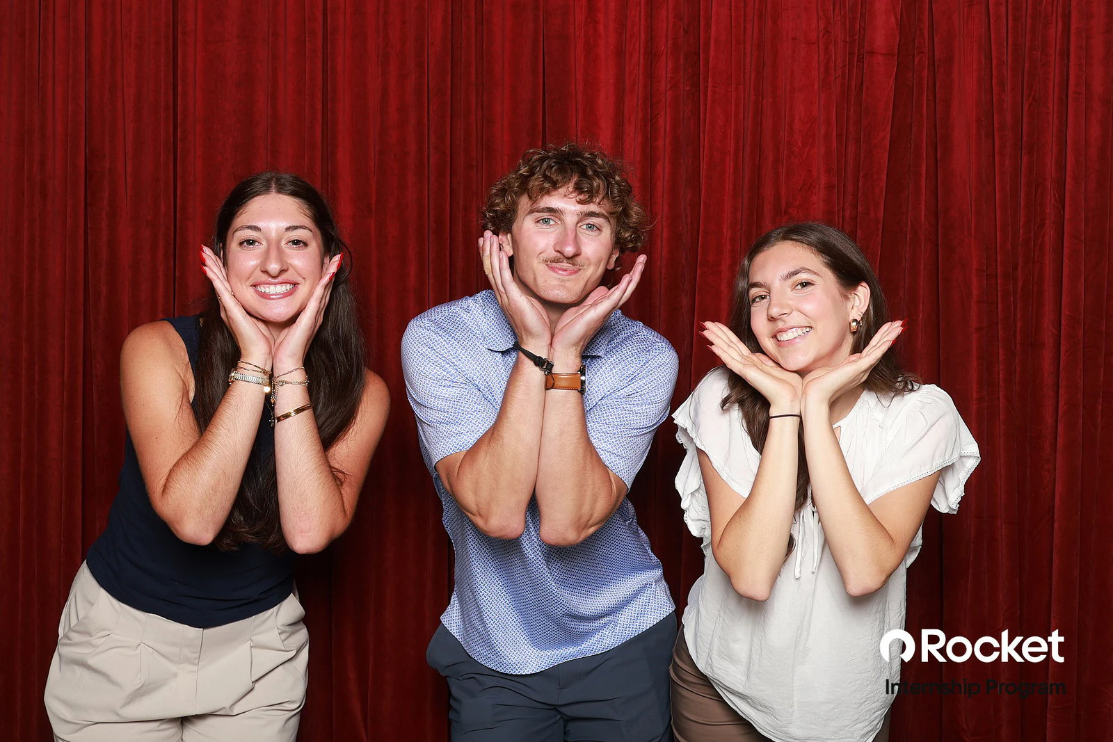 Two young women and a young man with their hands framing their faces at Intern Open House with Rocket