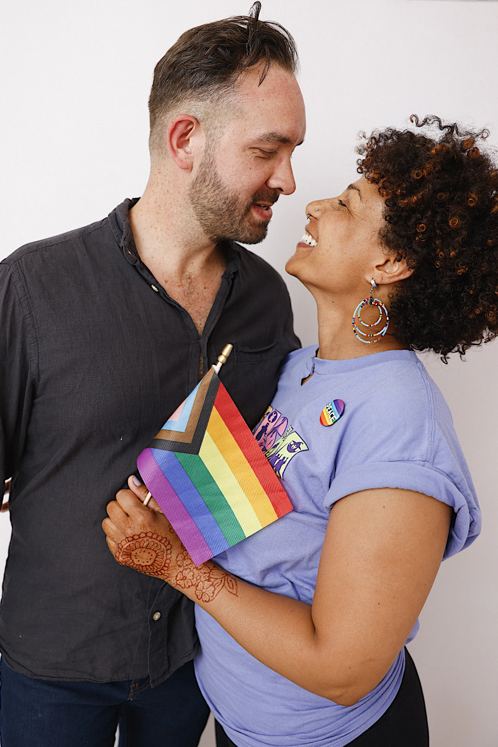 Couple with a Pride flag at My Chosen Family Portraits at Motor City Pride 2025