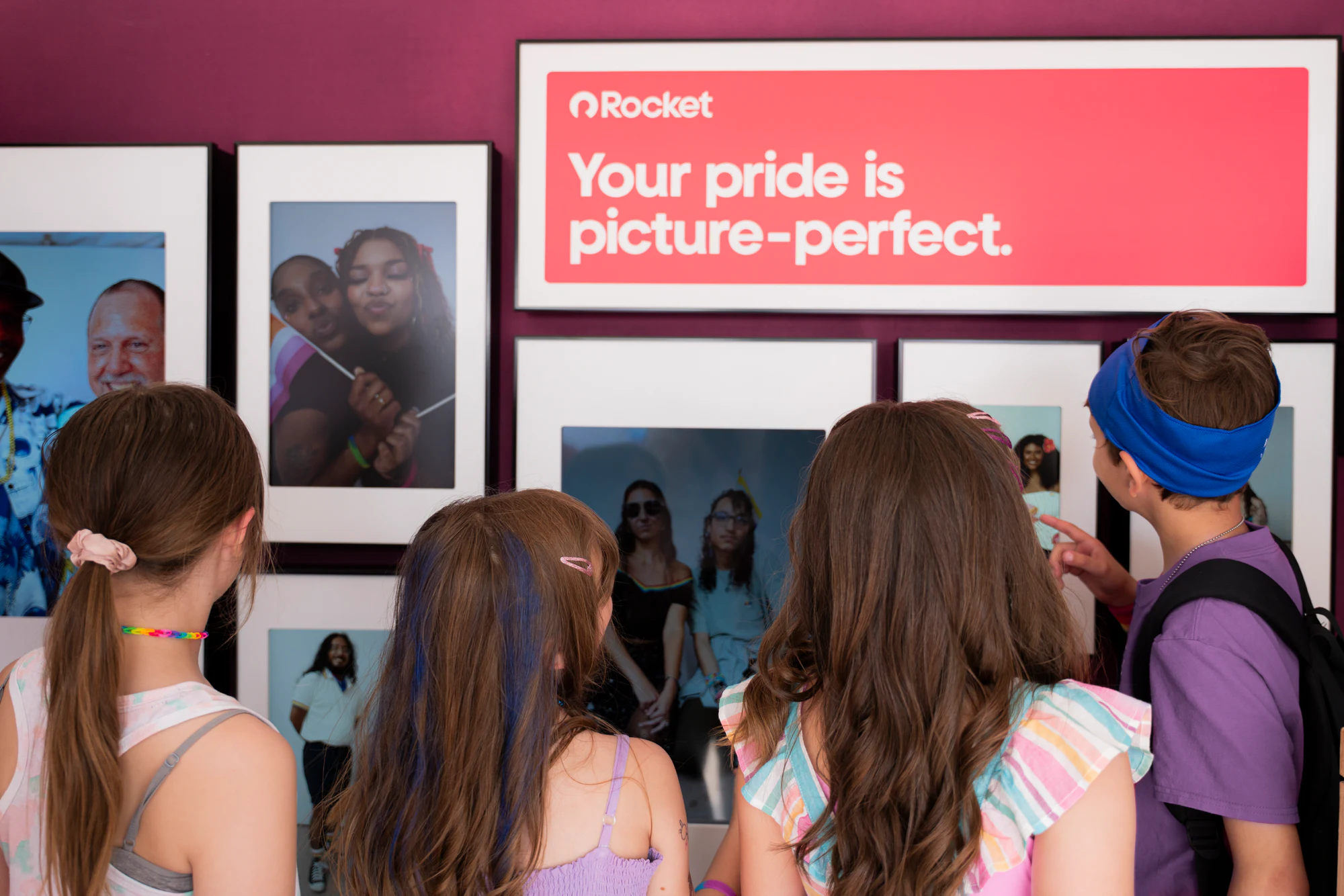 Kids looking at the gallery wall at My Chosen Family Portraits at Motor City Pride 2025