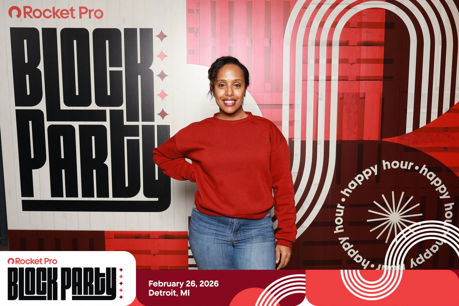 A woman in a red sweatshirt with a hand on her hip in front of the printed wall at Rocket Pro Block Party