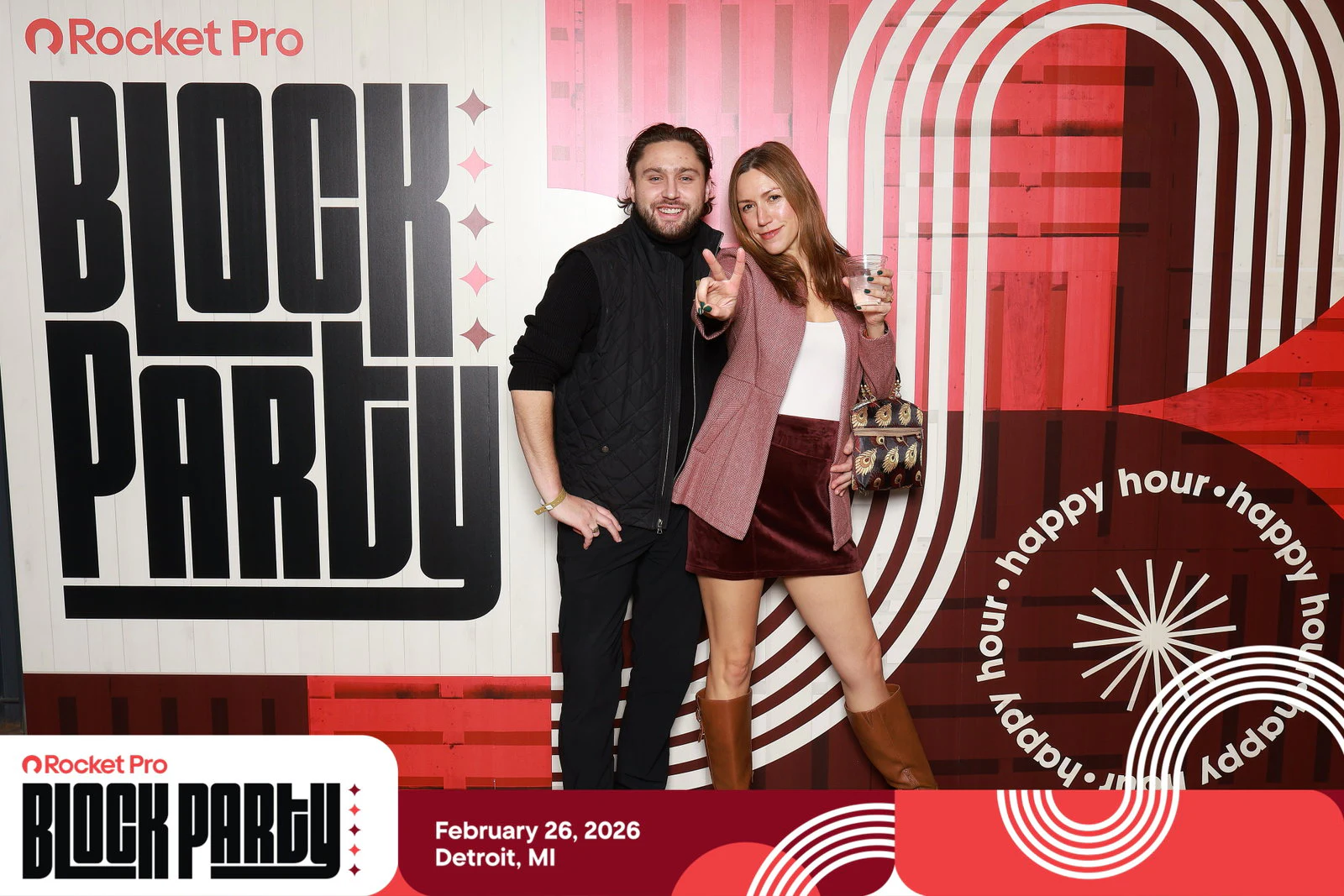 A man in a black vest and a woman in a pink jacket and velvet skirt, she throws a peace sign at Rocket Pro Block Party