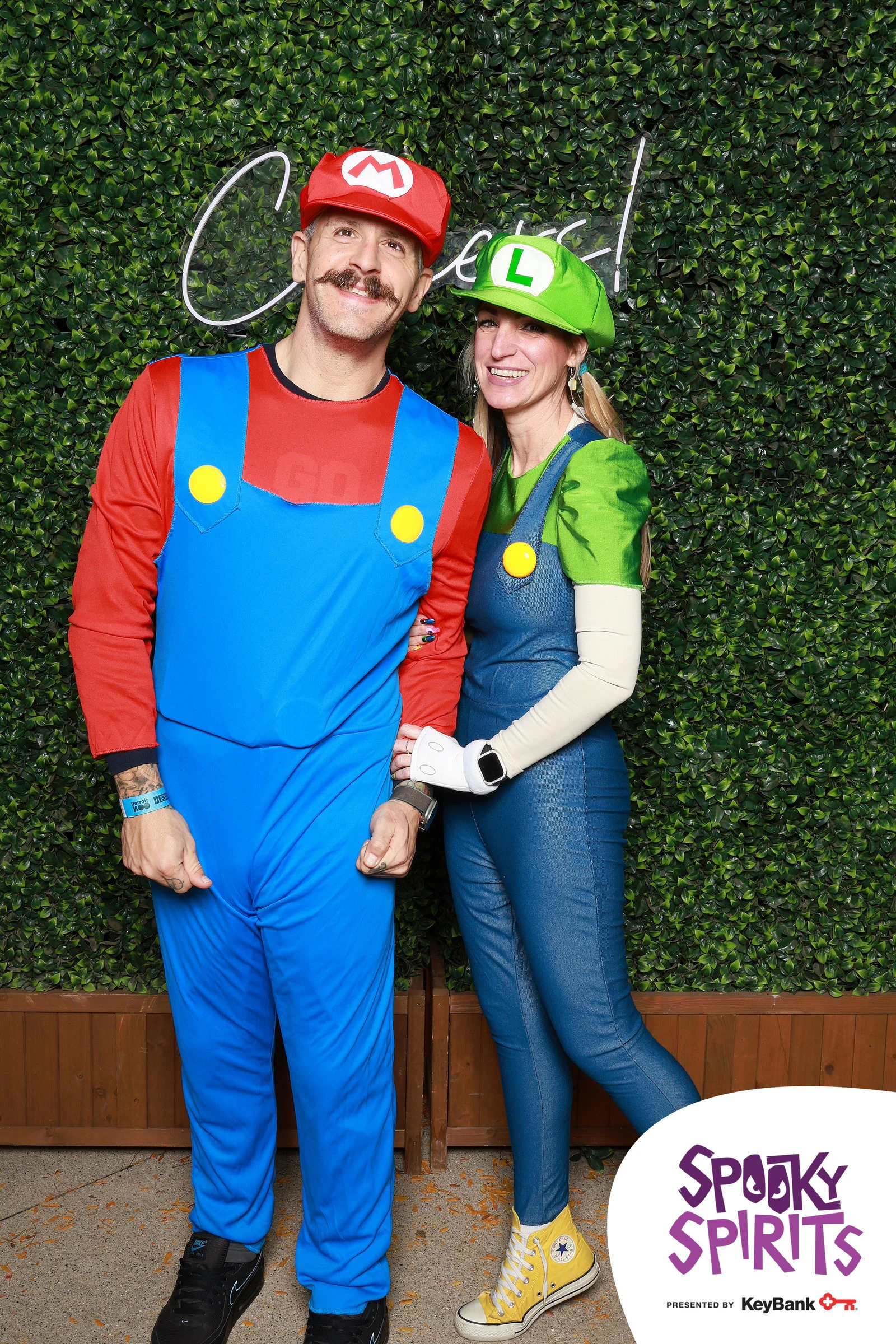 A man dressed as Mario and a woman dressed as Luigi in front of the boxwood wall and the Cheers! sign at Spooky Spirits at the Detroit Zoo 2026