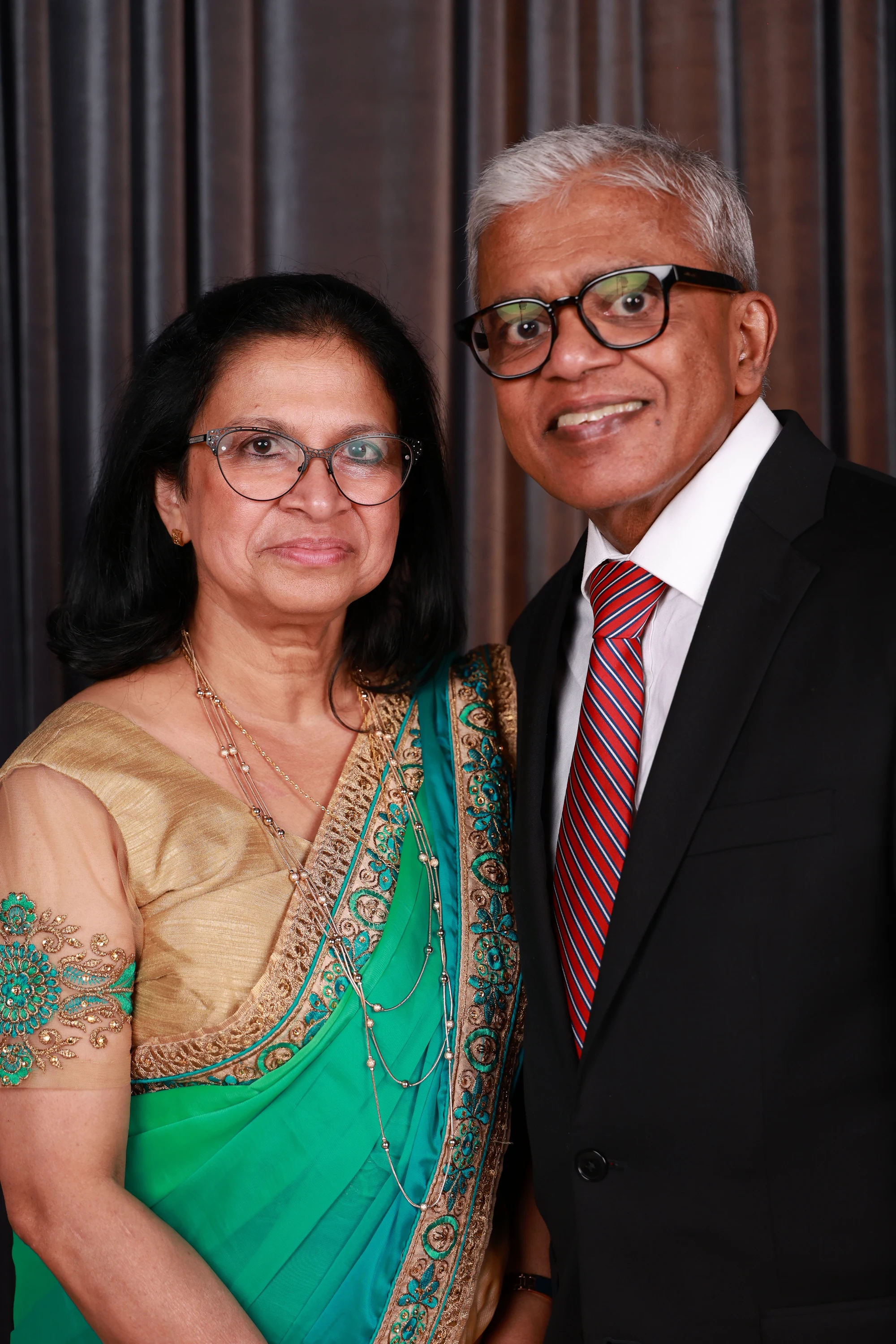 Older couple, green sari and a red tie, both smiling at Puja + Curtis at State Savings Bank