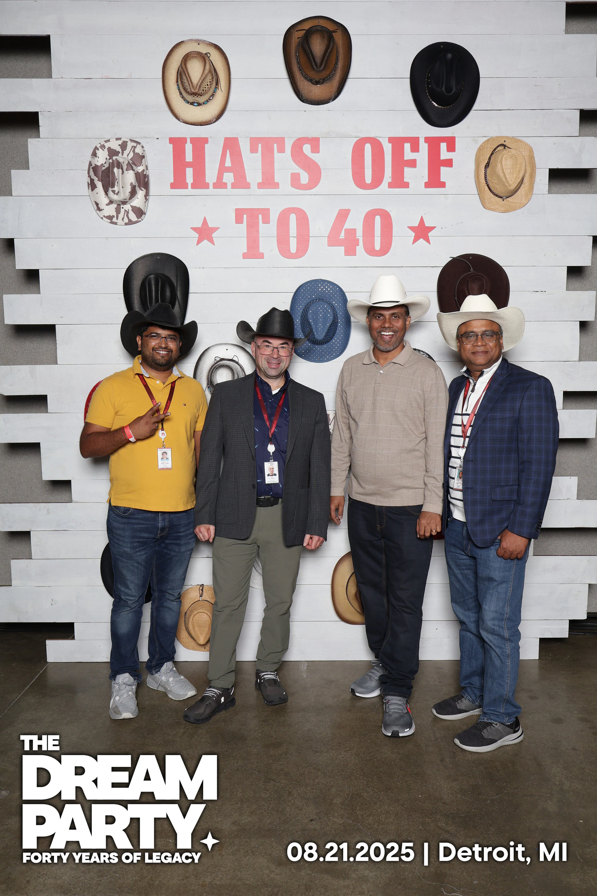 Four coworkers in cowboy hats and lanyards lined up at the Hats Off to 40 wall at The Dream Party: Rocket at 40