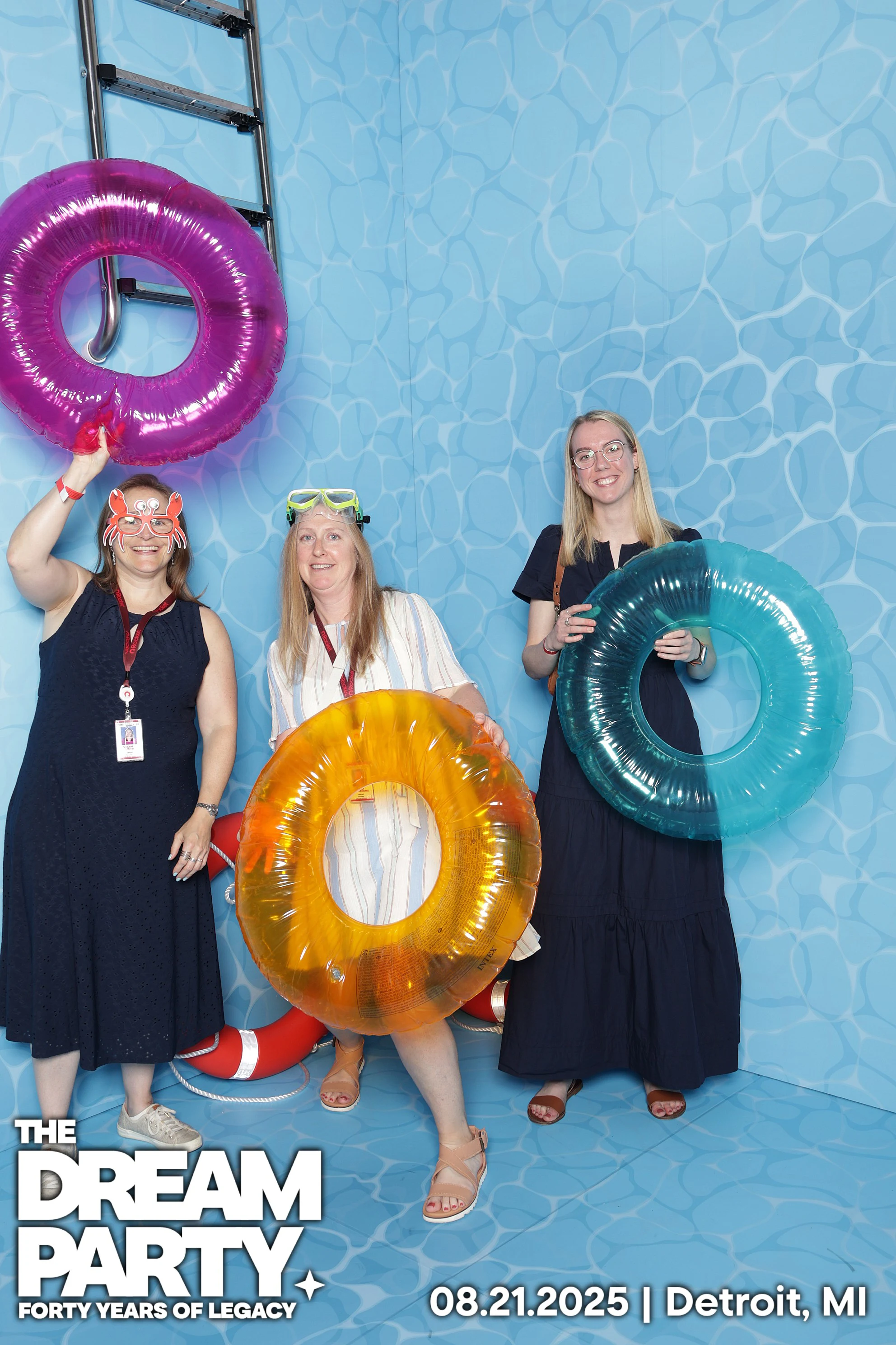 Three guests holding pink, orange and teal inner tubes in the pool set at The Dream Party: Rocket at 40