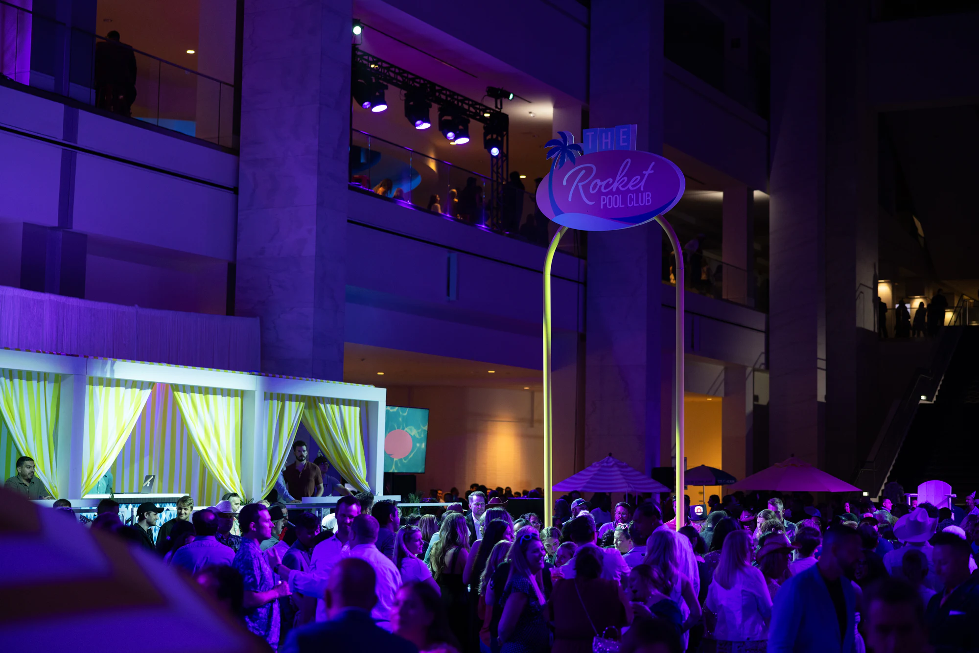 A packed crowd in purple light under the Rocket Pool Club sign at The Dream Party: Rocket at 40