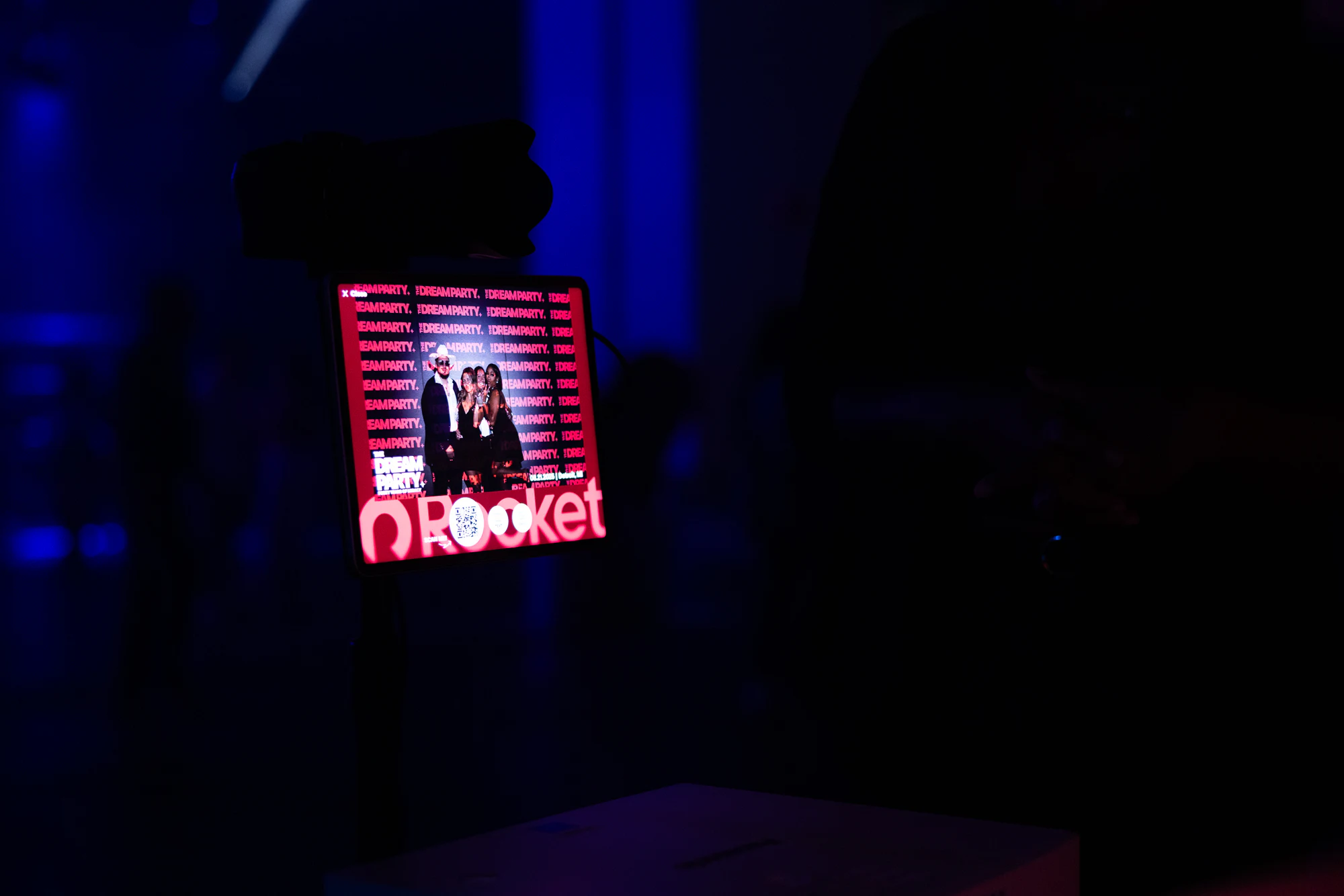 The booth screen glowing in the dark, showing a guest photo with the Rocket logo at The Dream Party: Rocket at 40