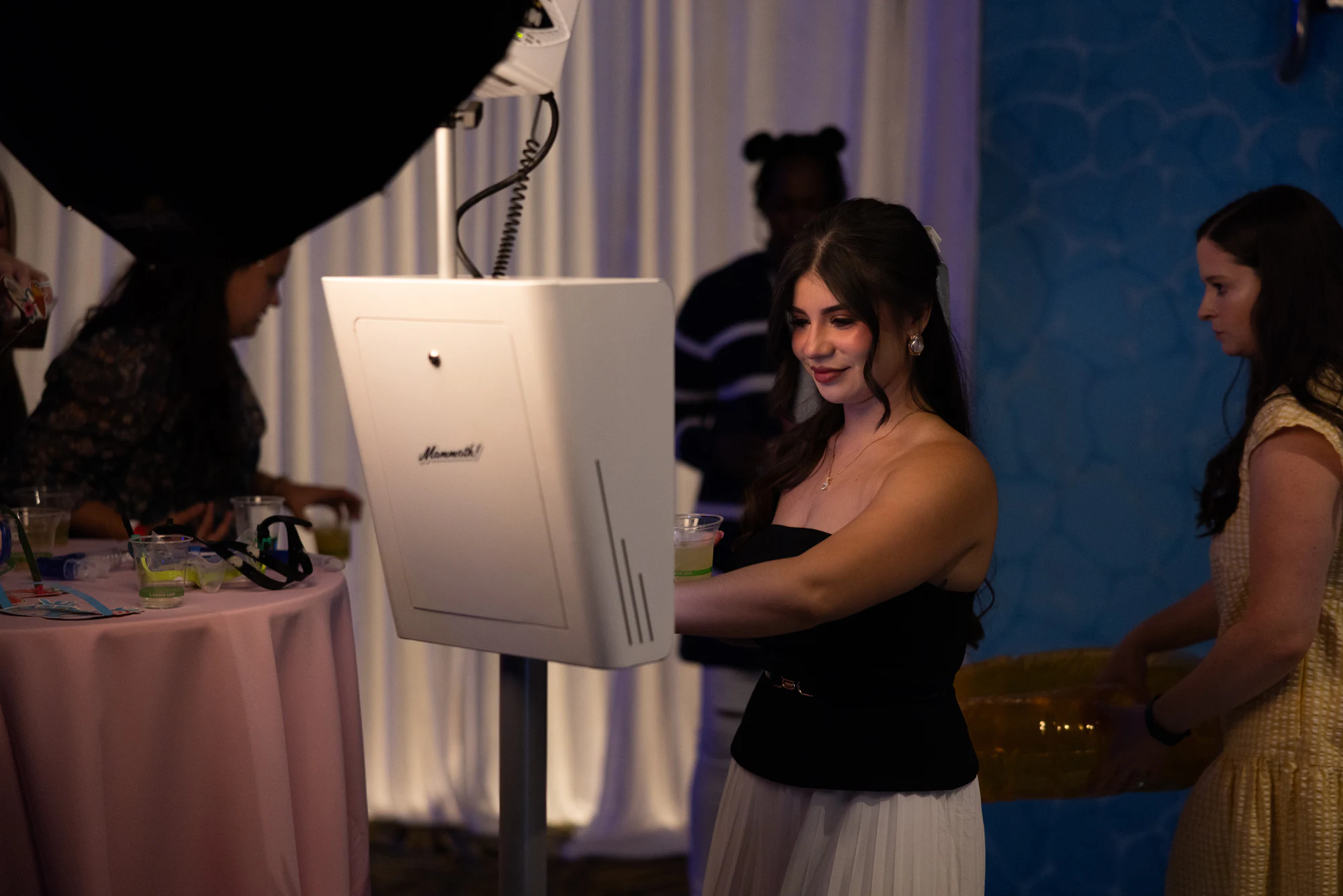 A guest with a drink looking at her photos on the white booth kiosk at The Dream Party: Rocket at 40