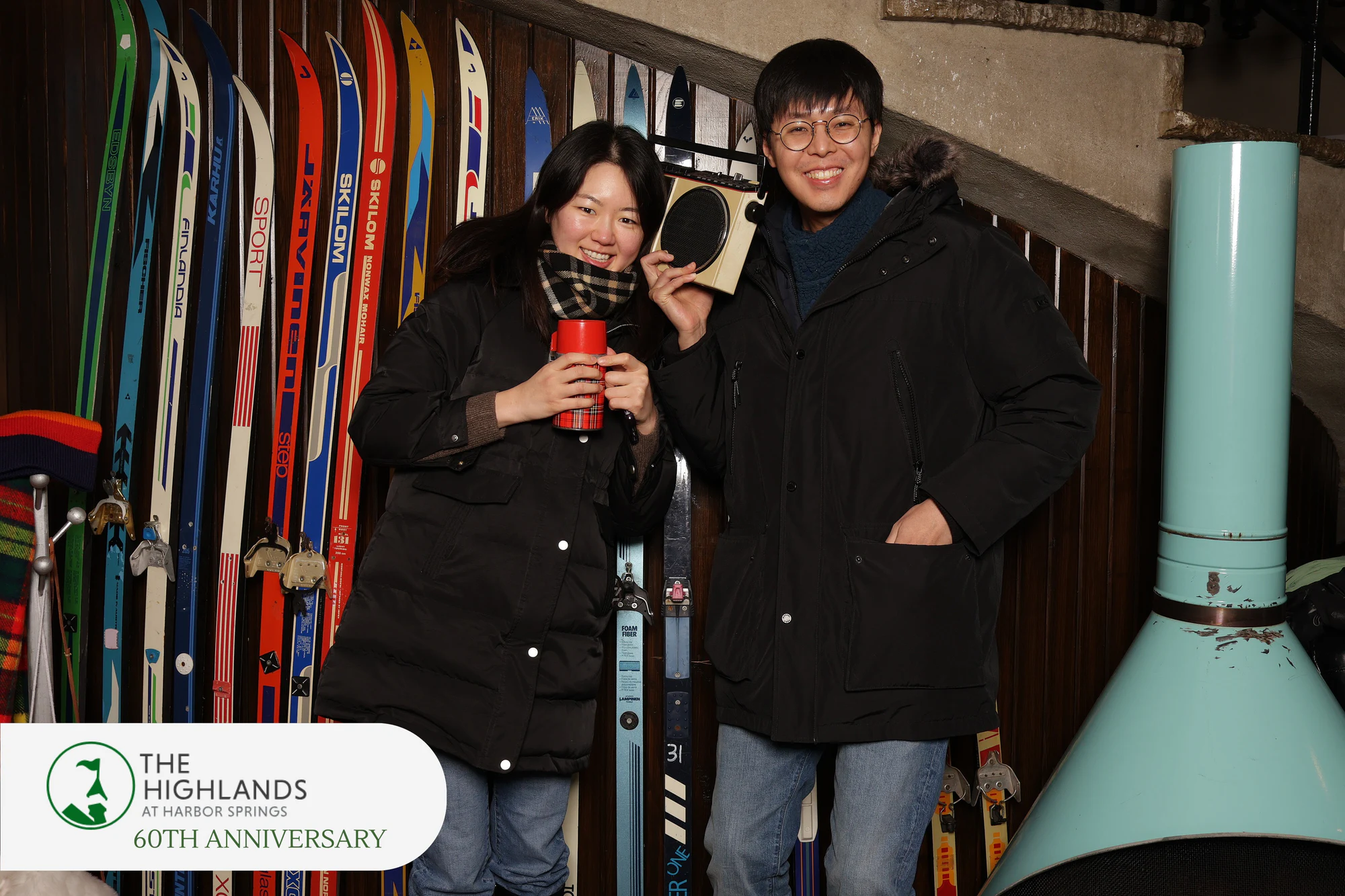 Couple in black parkas, she with a red cup, he holding up the boombox at The Highlands 60th Anniversary