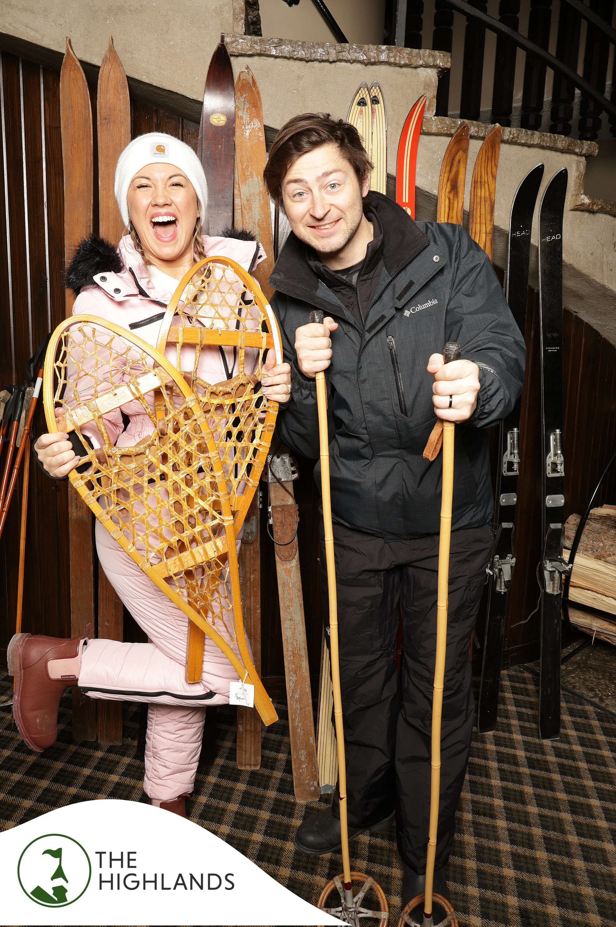 The couple laughing, she holding up a wooden snowshoe at The Highlands 61st Anniversary