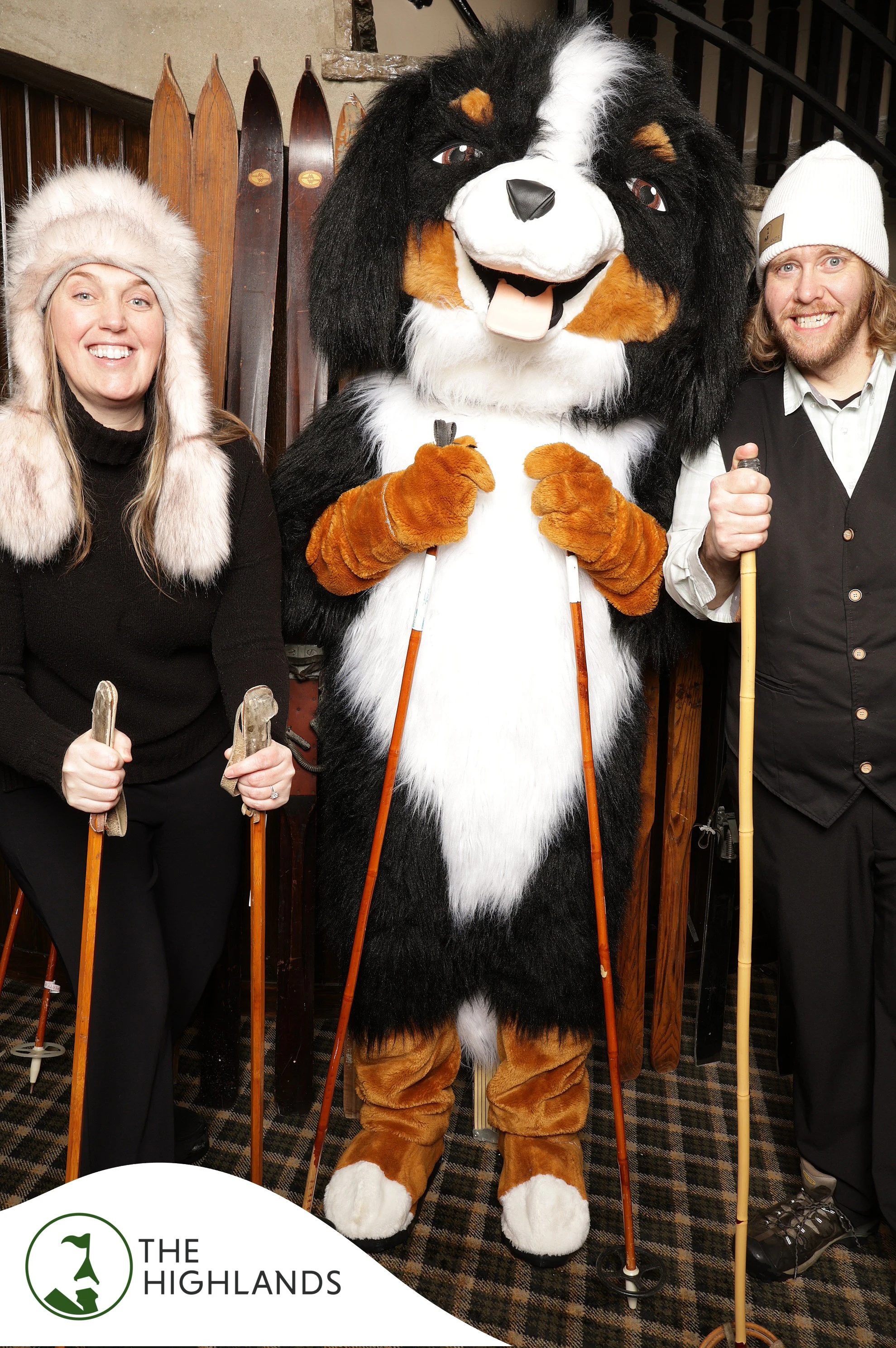 The woman, the dog mascot and the man each holding a vintage ski pole at The Highlands 61st Anniversary