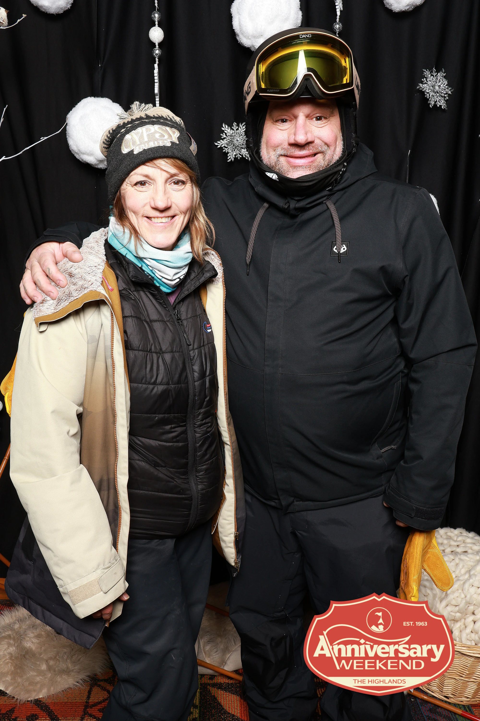 The couple in ski kit, his arm around her shoulders at The Highlands Anniversary Weekend