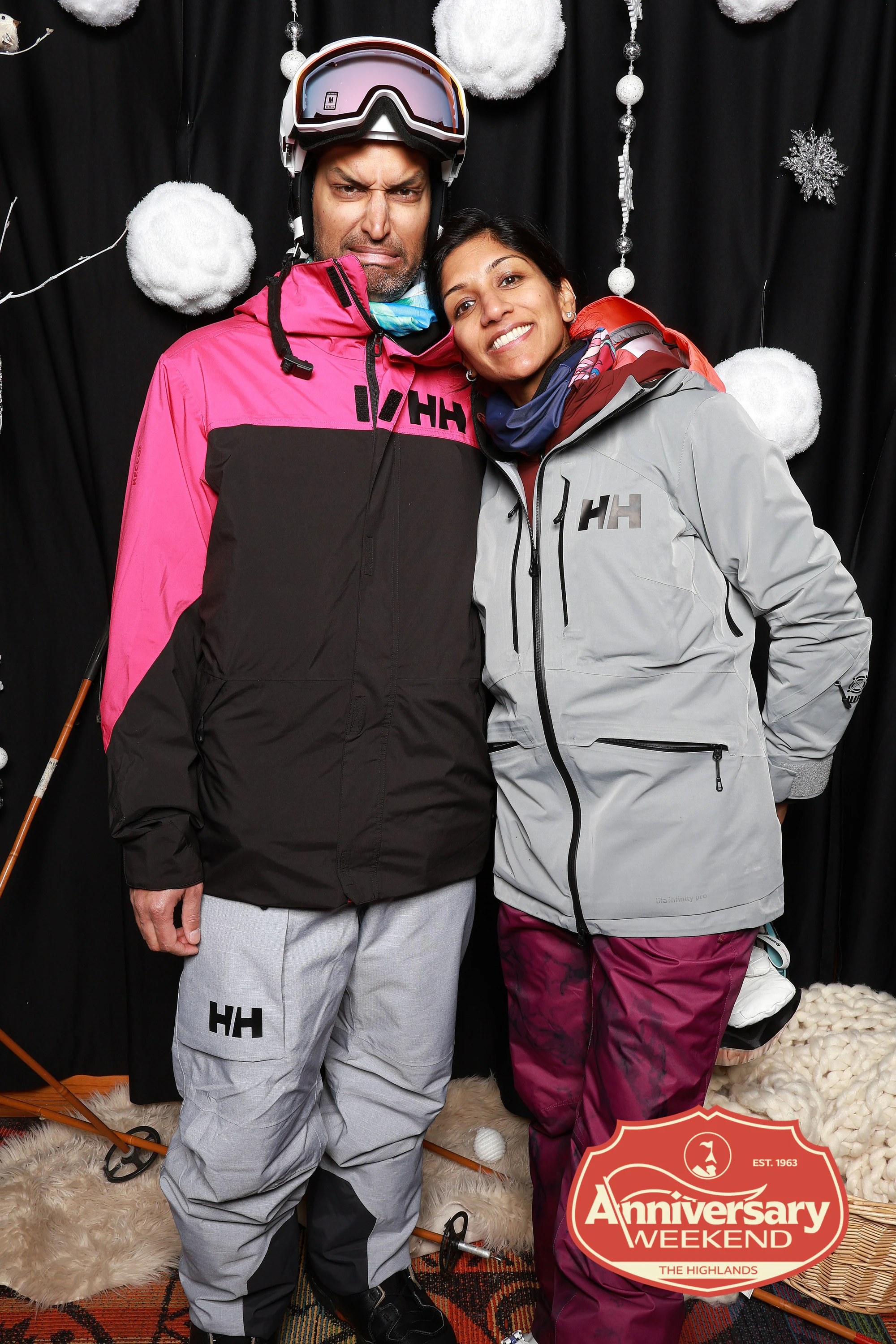 The couple in ski jackets pulling faces at The Highlands Anniversary Weekend