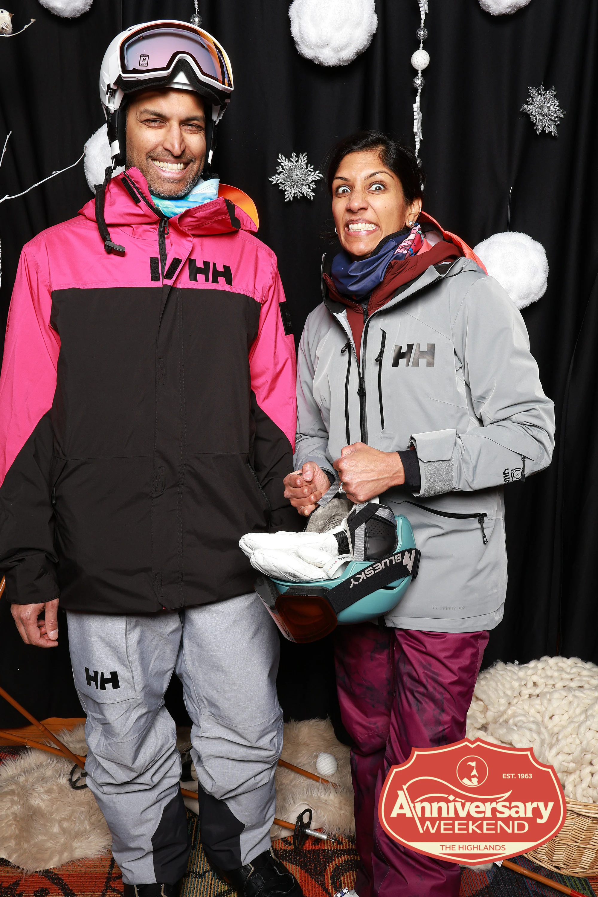 The couple in ski jackets, she holding her helmet and making a face at The Highlands Anniversary Weekend