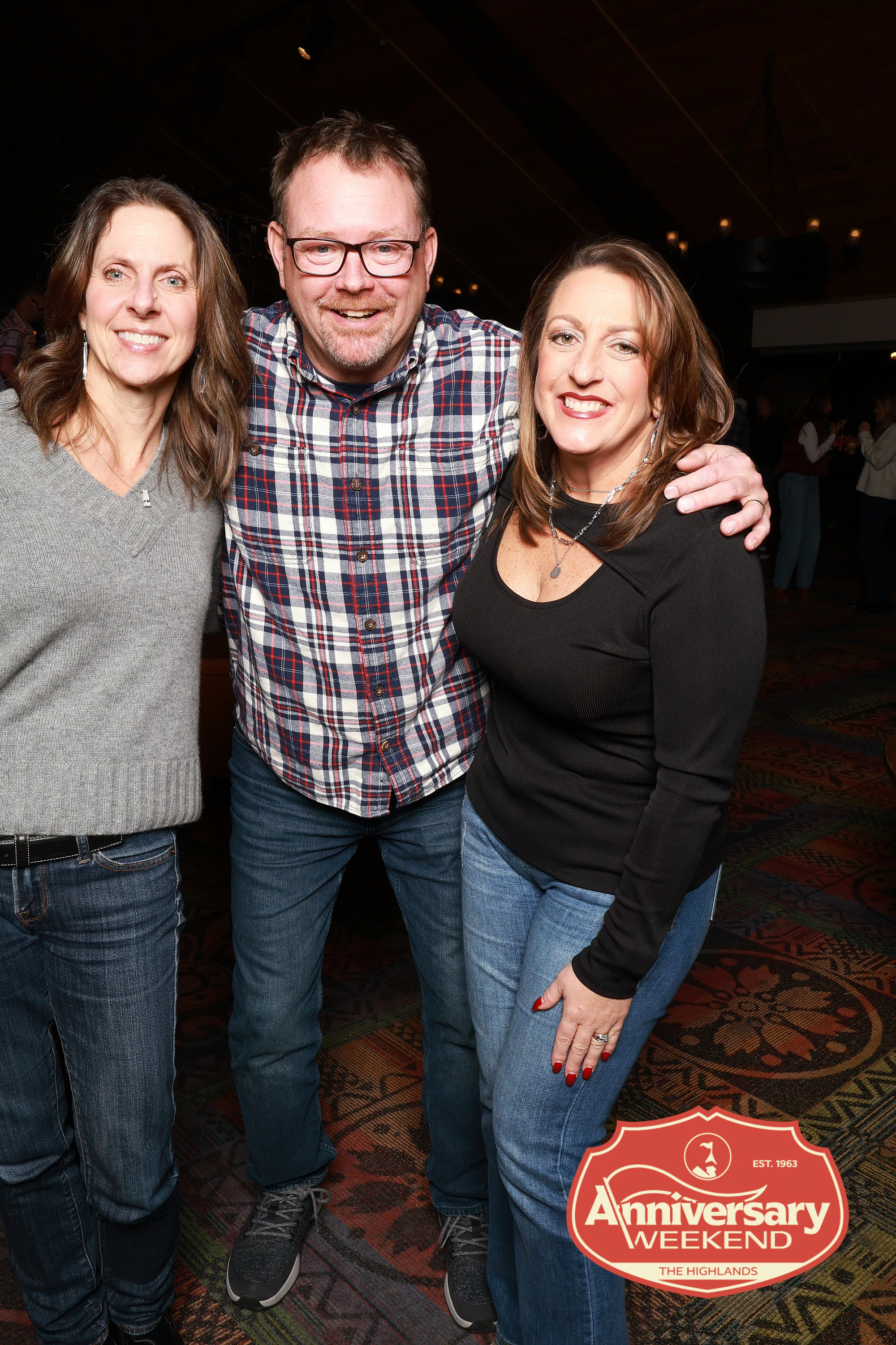 The three friends at the evening party smiling, arms around each other at The Highlands Anniversary Weekend