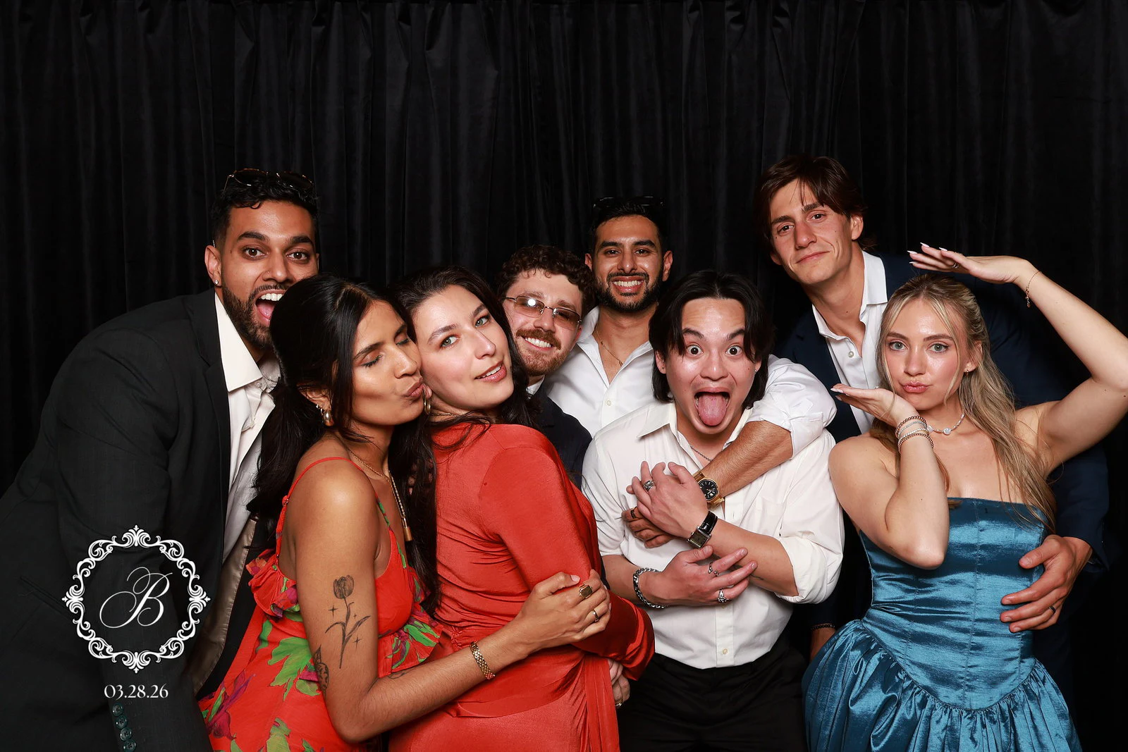 Eight friends in a tight huddle, one sticking his tongue out and one kissing a friend’s cheek at Tianna + Krishna