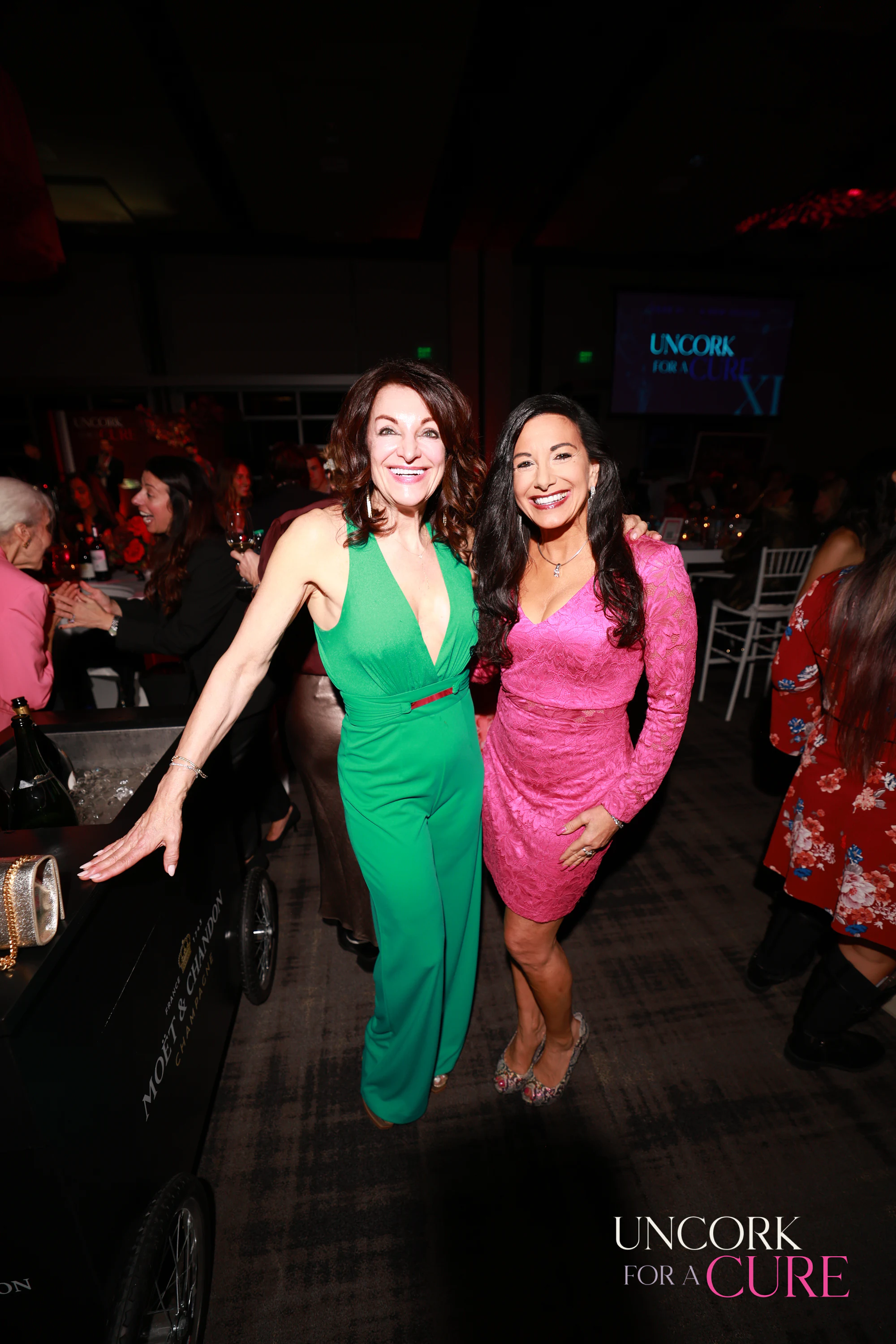 Two women in green and pink dancing together at Uncork for a Cure 2026