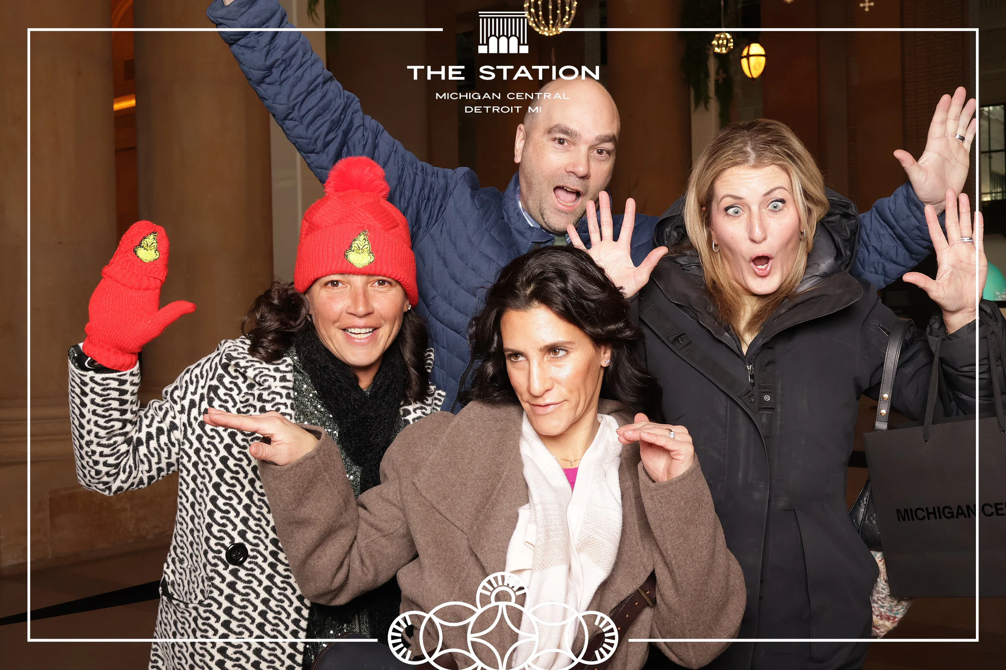 Five friends with their hands up, one in a red hat and mittens at Winter at the Station, Michigan Central