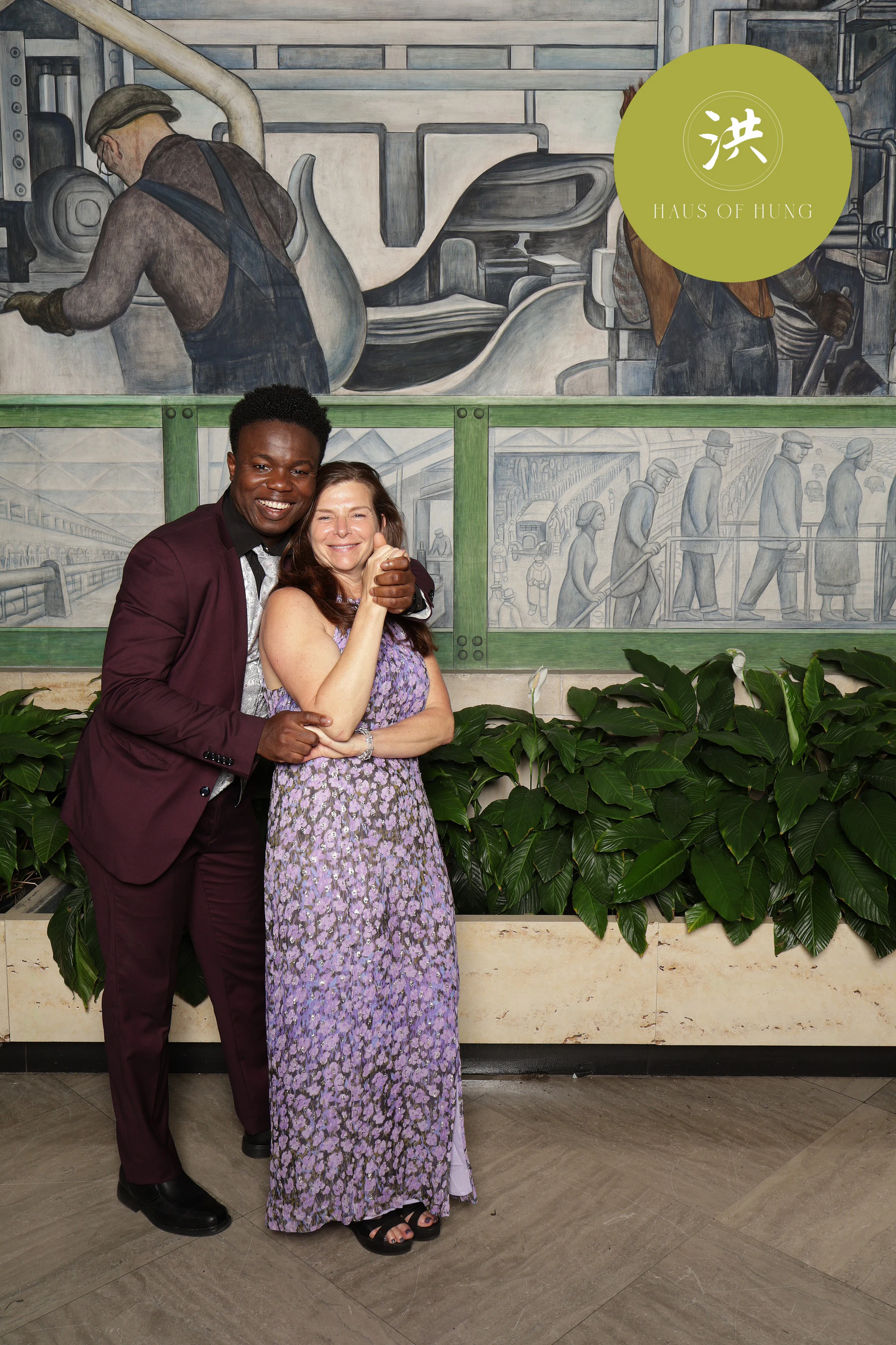 Couple hugging with the mural behind them at Lesley + Kevin at the Detroit Institute of Arts